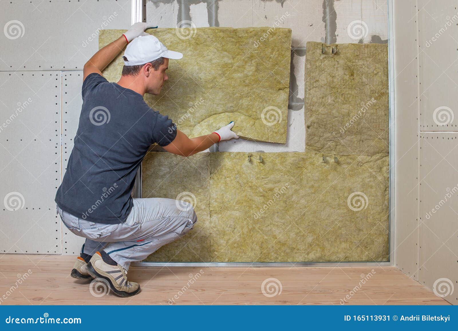Worker insulating a room wall with mineral rock wool thermal insulation., Stock image