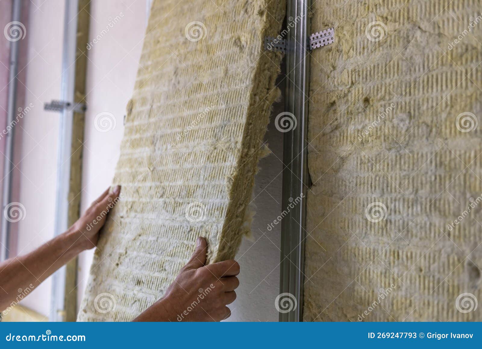 Worker insulating a room wall with mineral rock wool thermal insulation., Stock image