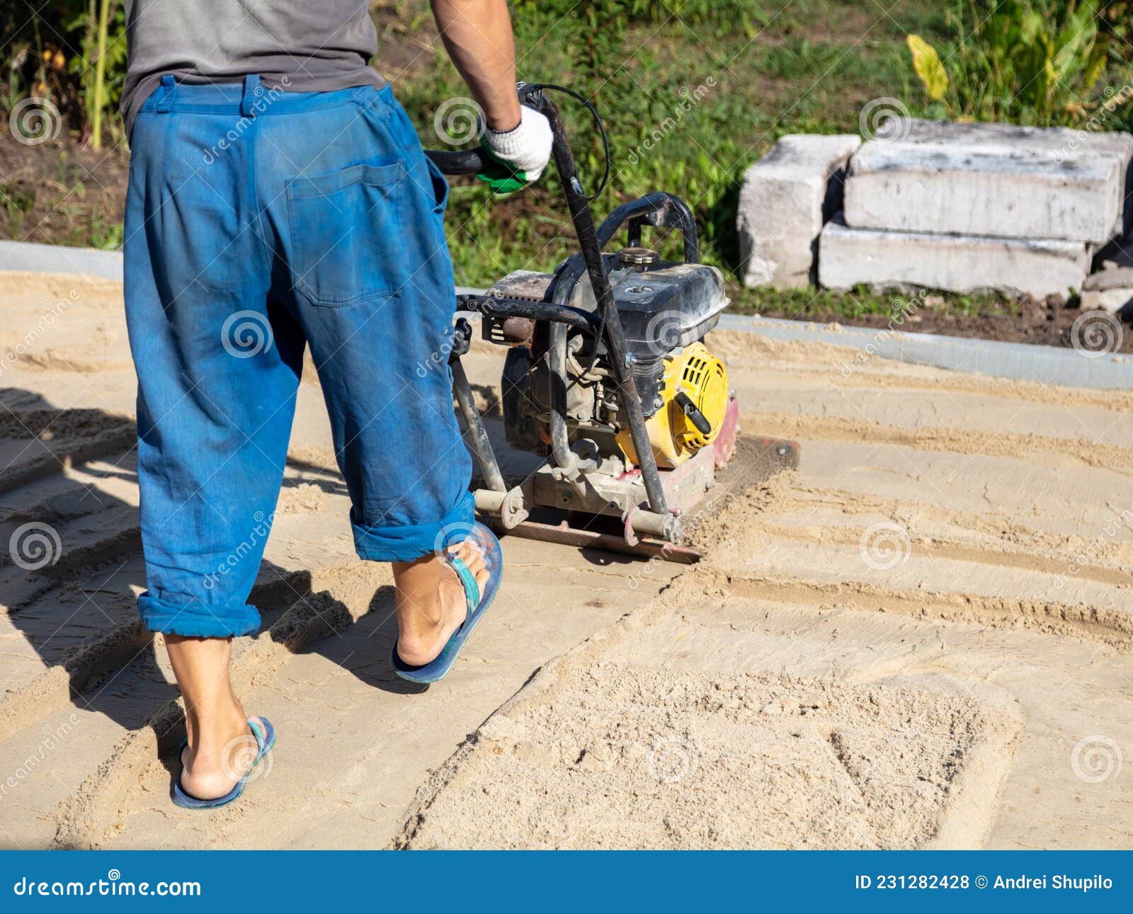 A Worker Lays Down Gravel and Sand for Paving Slabs. Stock Photo