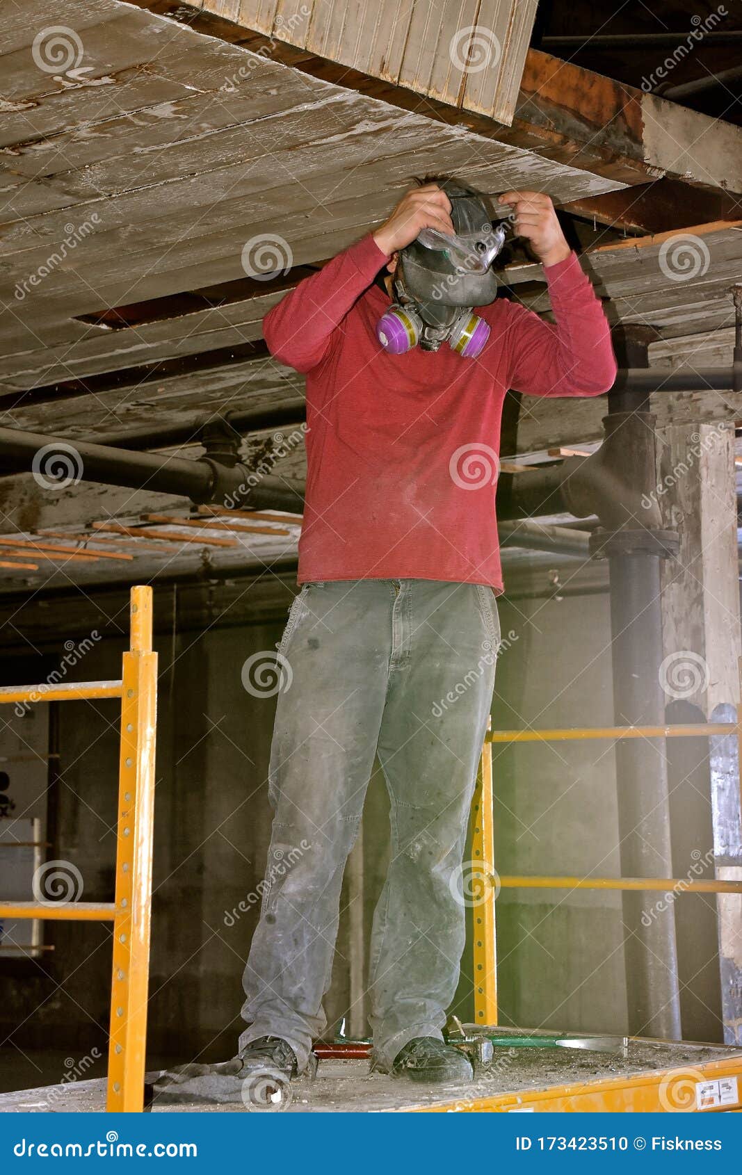 Worker on a Lift Adjust a Dust Mask in a Renovation of an Old Warehouse. Stock Photo Image of