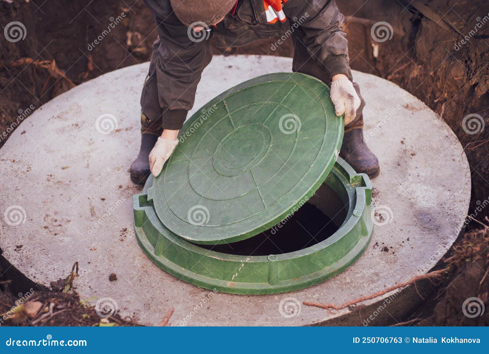 A Worker Lifts The Manhole Cover Of A Sewer Well. Construction And ...