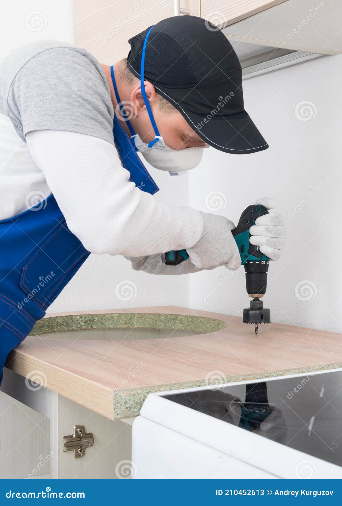 A Worker Makes a Hole in the Countertop for a Kitchen Tap with a Tool