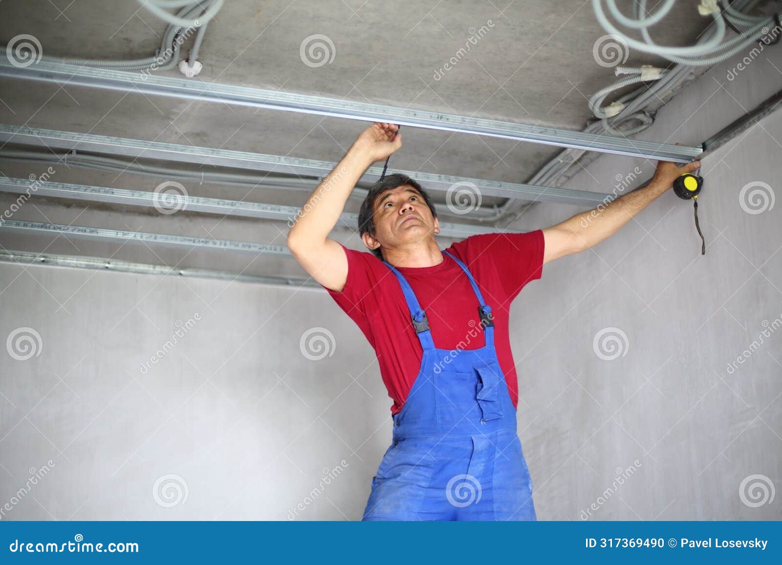 worker makes a mark on the ceiling profile using a