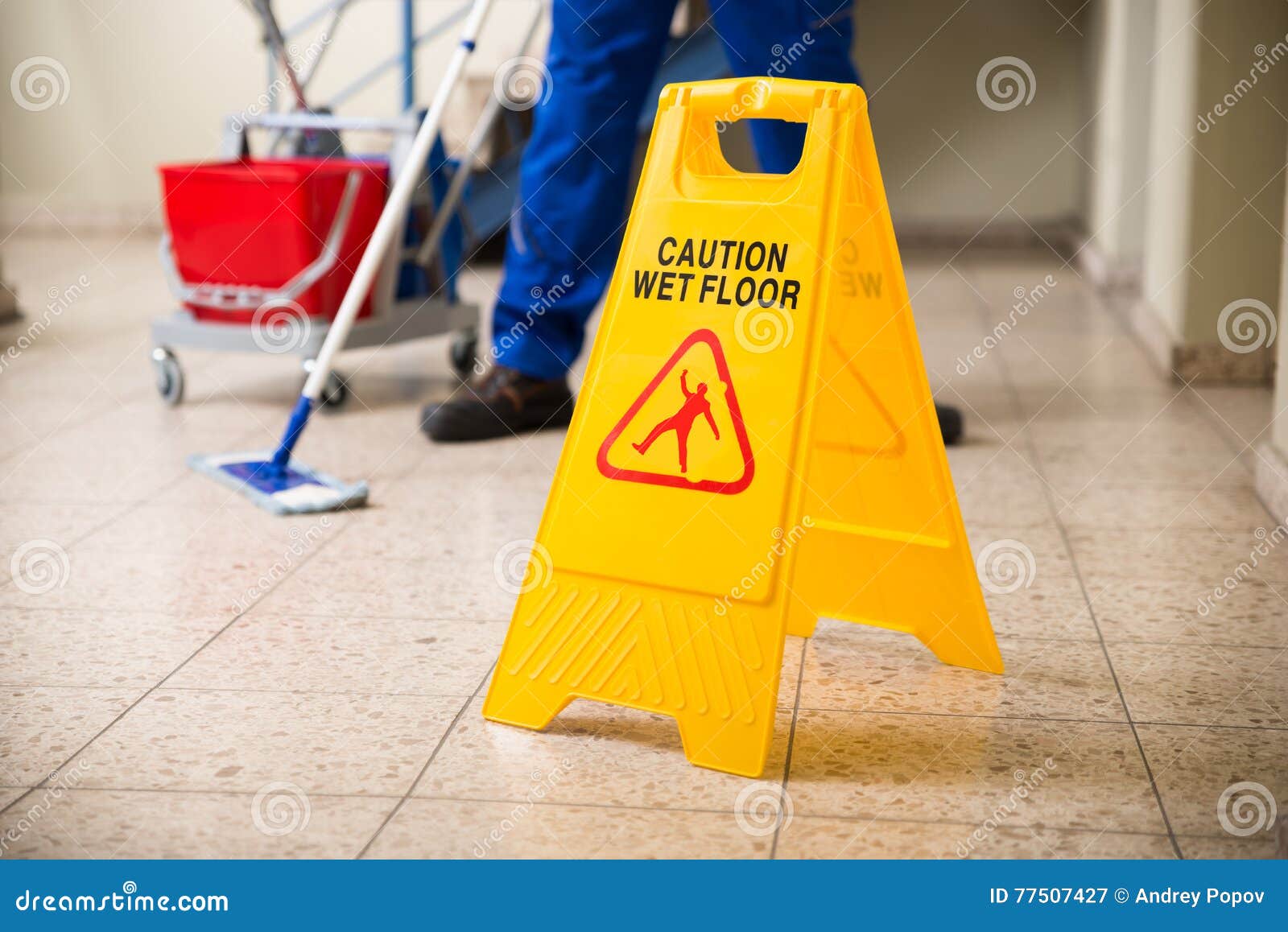 worker mopping floor with wet floor caution sign
