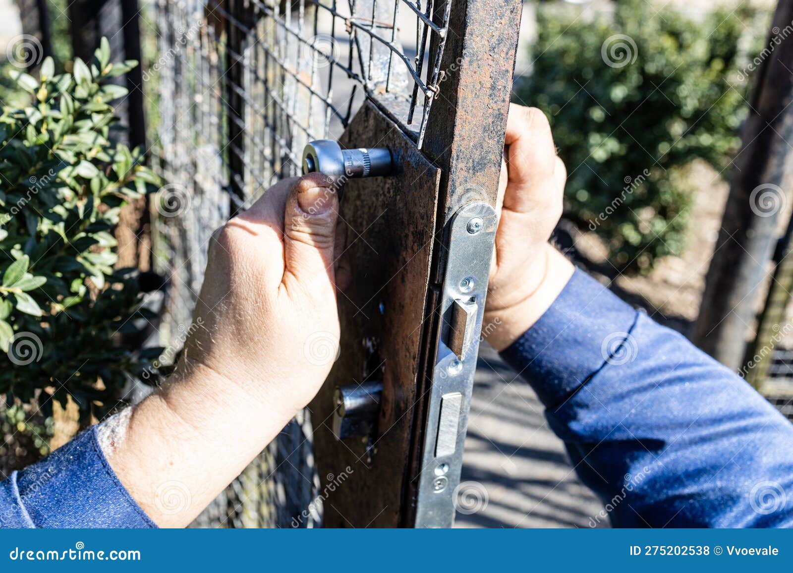 Worker Mounts New Door Lock in Iron Gate Close Up Stock Photo Image