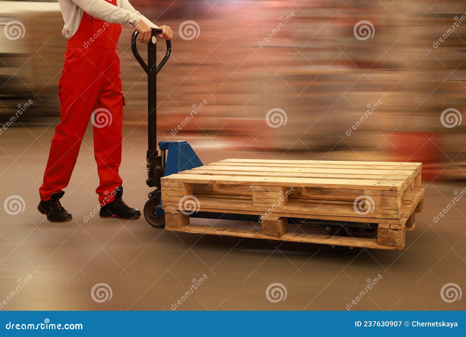 worker moving wooden pallets with manual forklift in warehouse, closeup