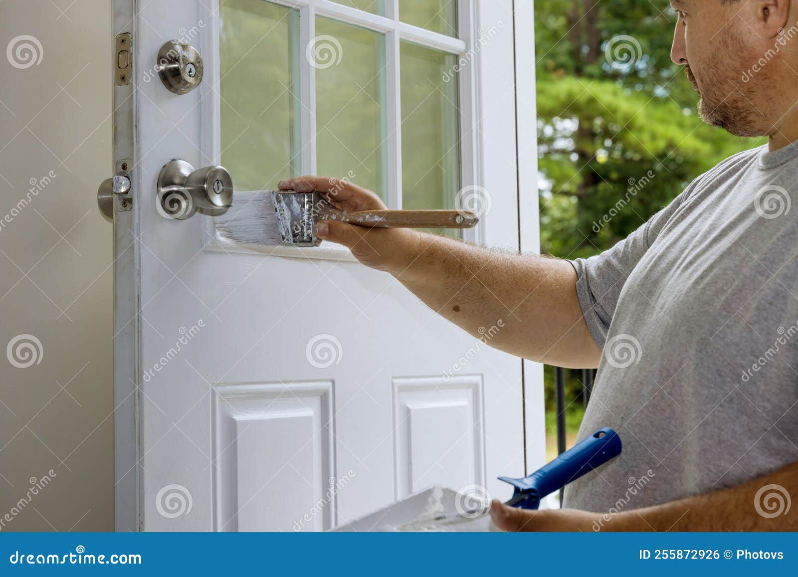 The Worker Painted a Wooden Front Door with a while Using a Paintbrush