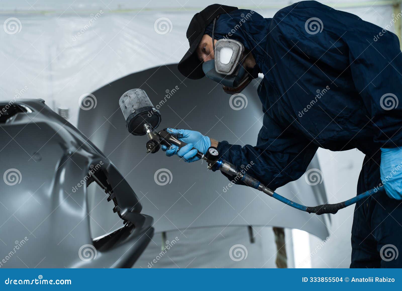worker is painting car in dark color with hvlp spray gun. auto mechanic is changing the color of vehicle using sponge