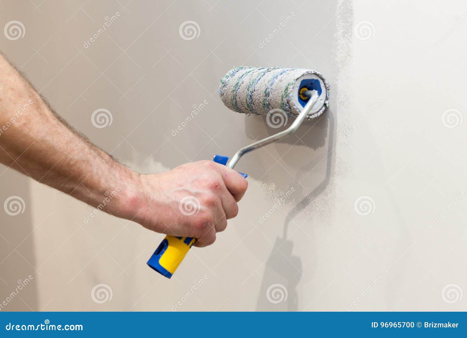 worker painting wall in room. painting walls with a roller.