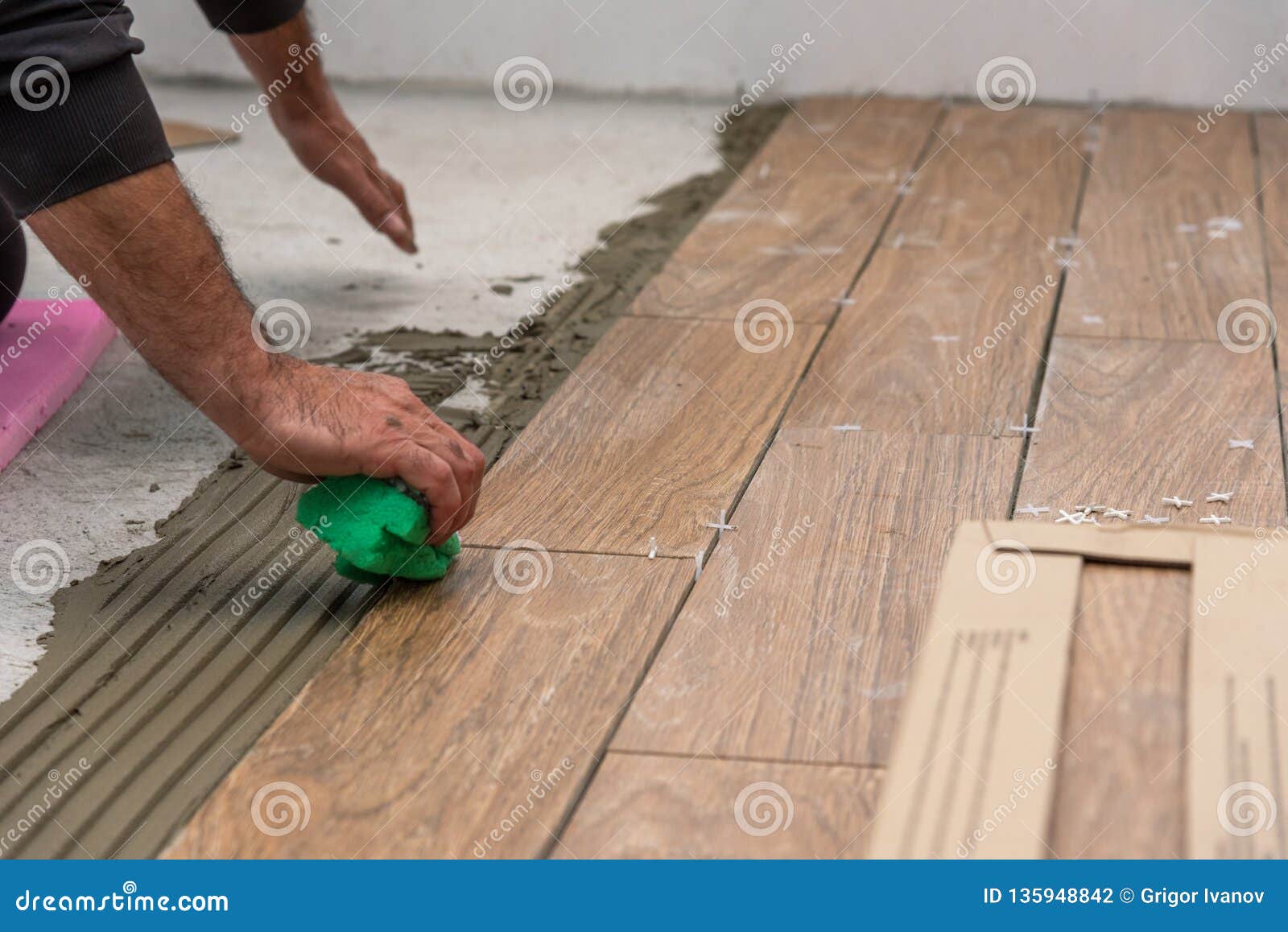 Worker Placing Ceramic Floor Tiles On Adhesive Surface Leveling