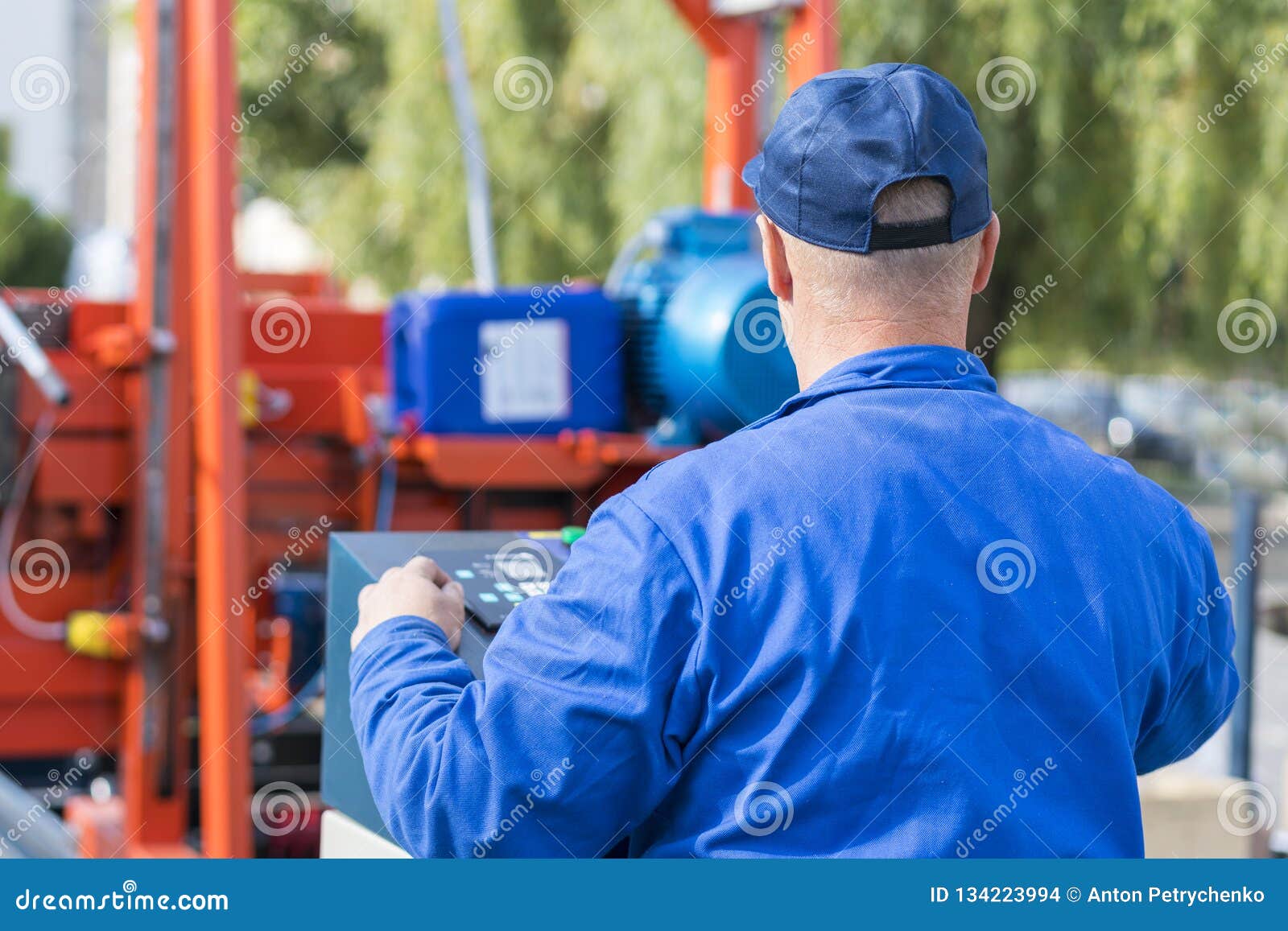 worker pressing buttons on cnc machine control board in factory