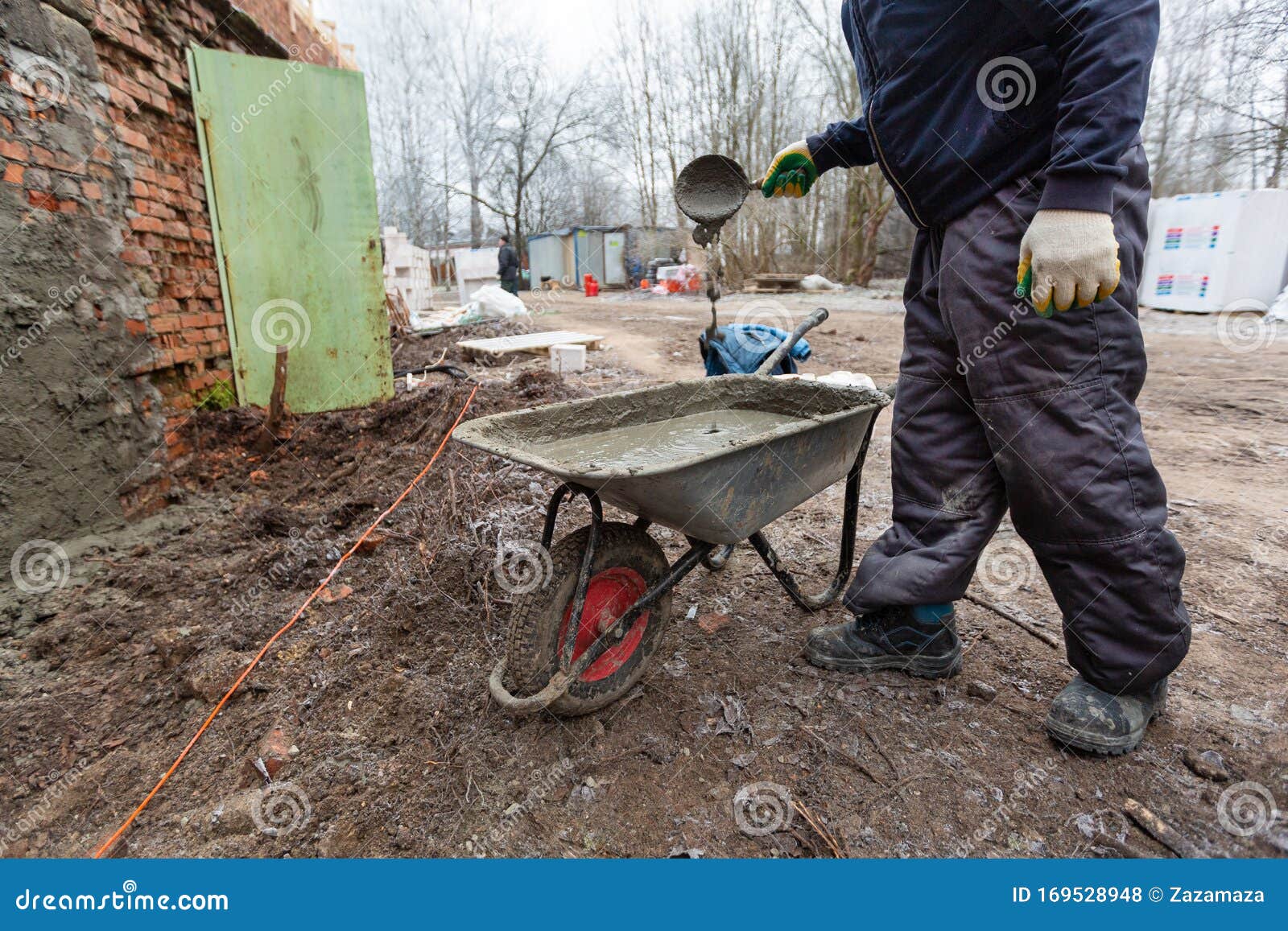 Worker in Protect Gloves is Mixing Up the Liquid Cement in Construction