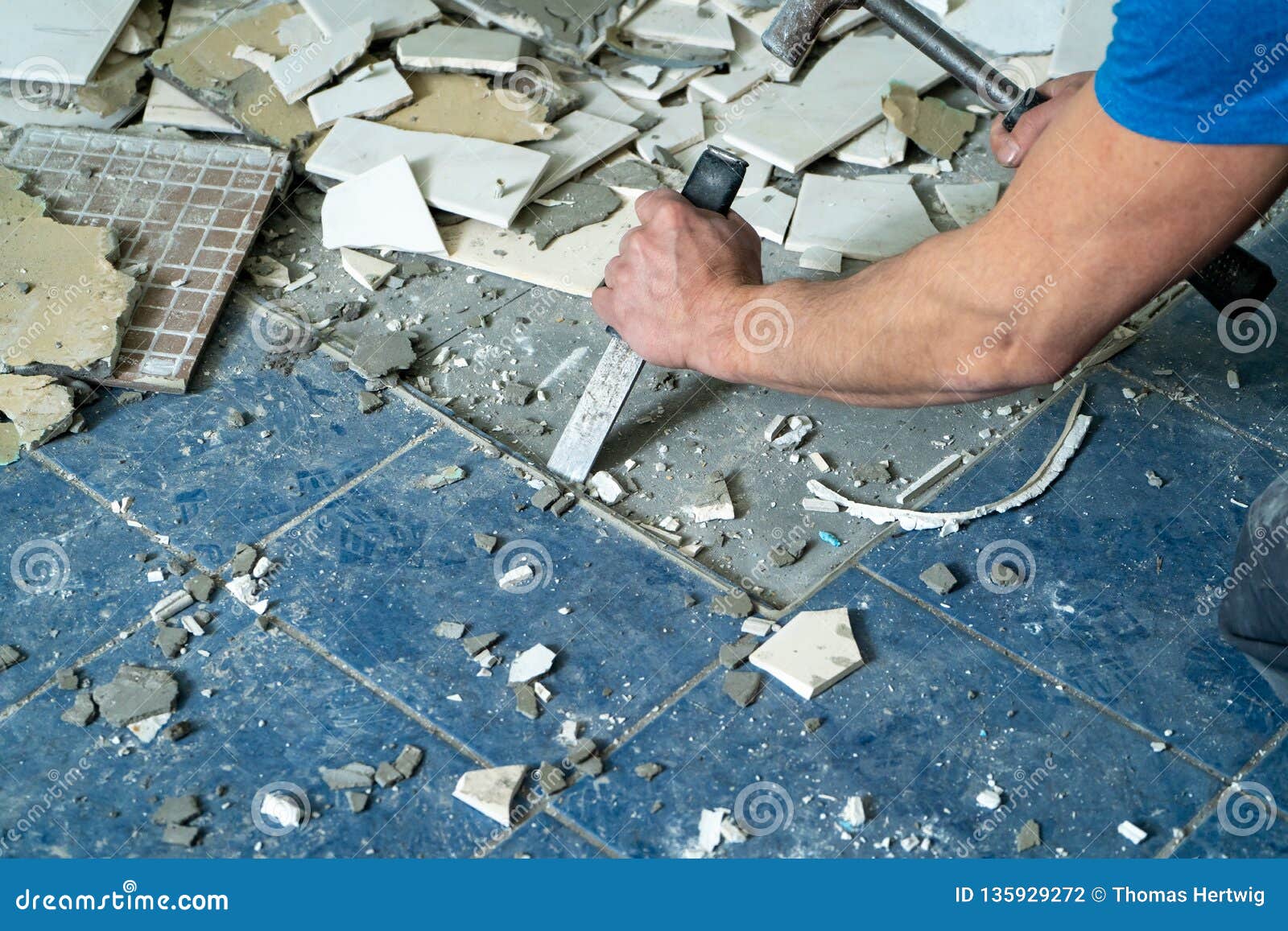 worker remove, demolish old tiles in a bathroom with hammer and chisel