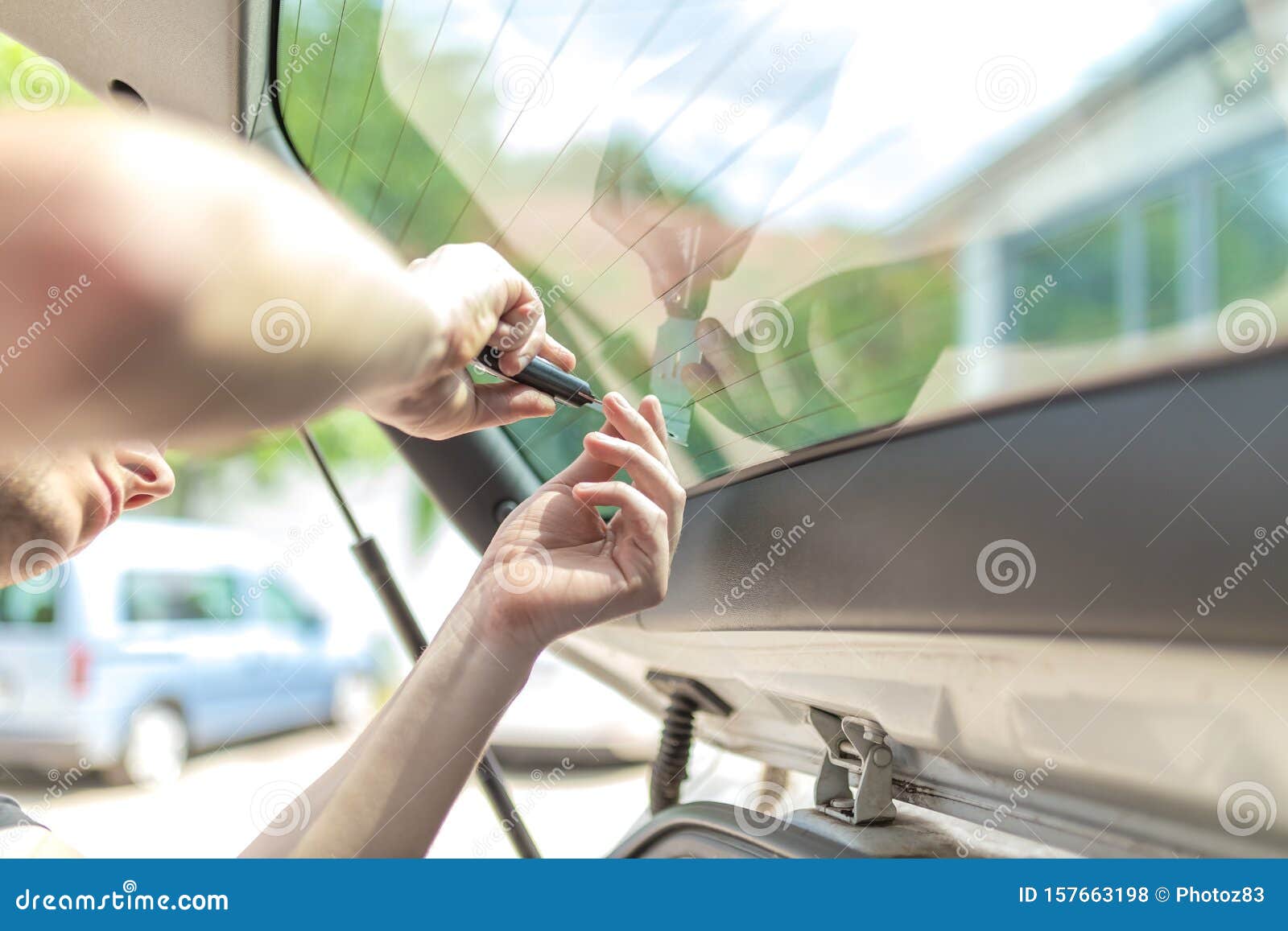 Tinted dark glass foil removal from car window. Stock Photo by