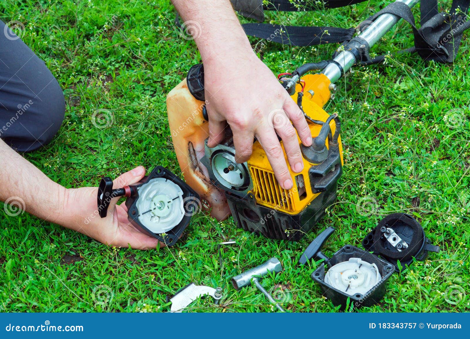 Worker Repairs a Starter in a Trimmer or Lawn Mower that Lies on the