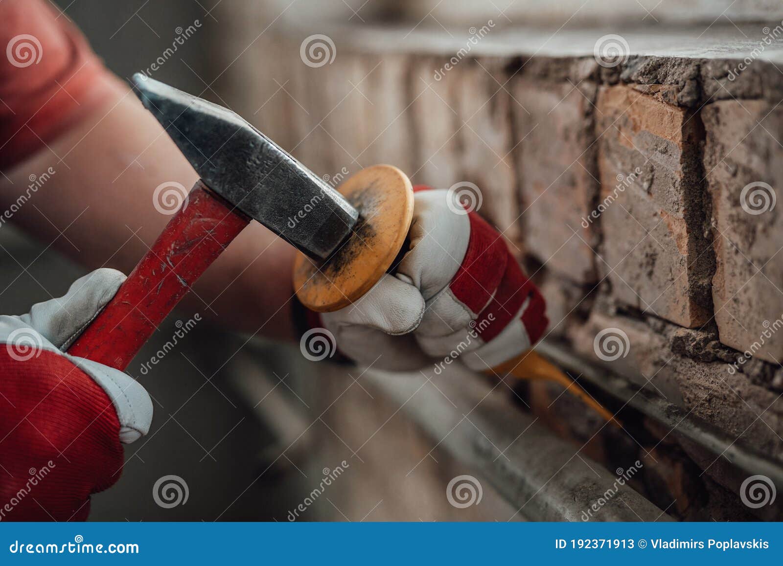 Builder`s Gloved Hands Working with Hammer and Chisel at the