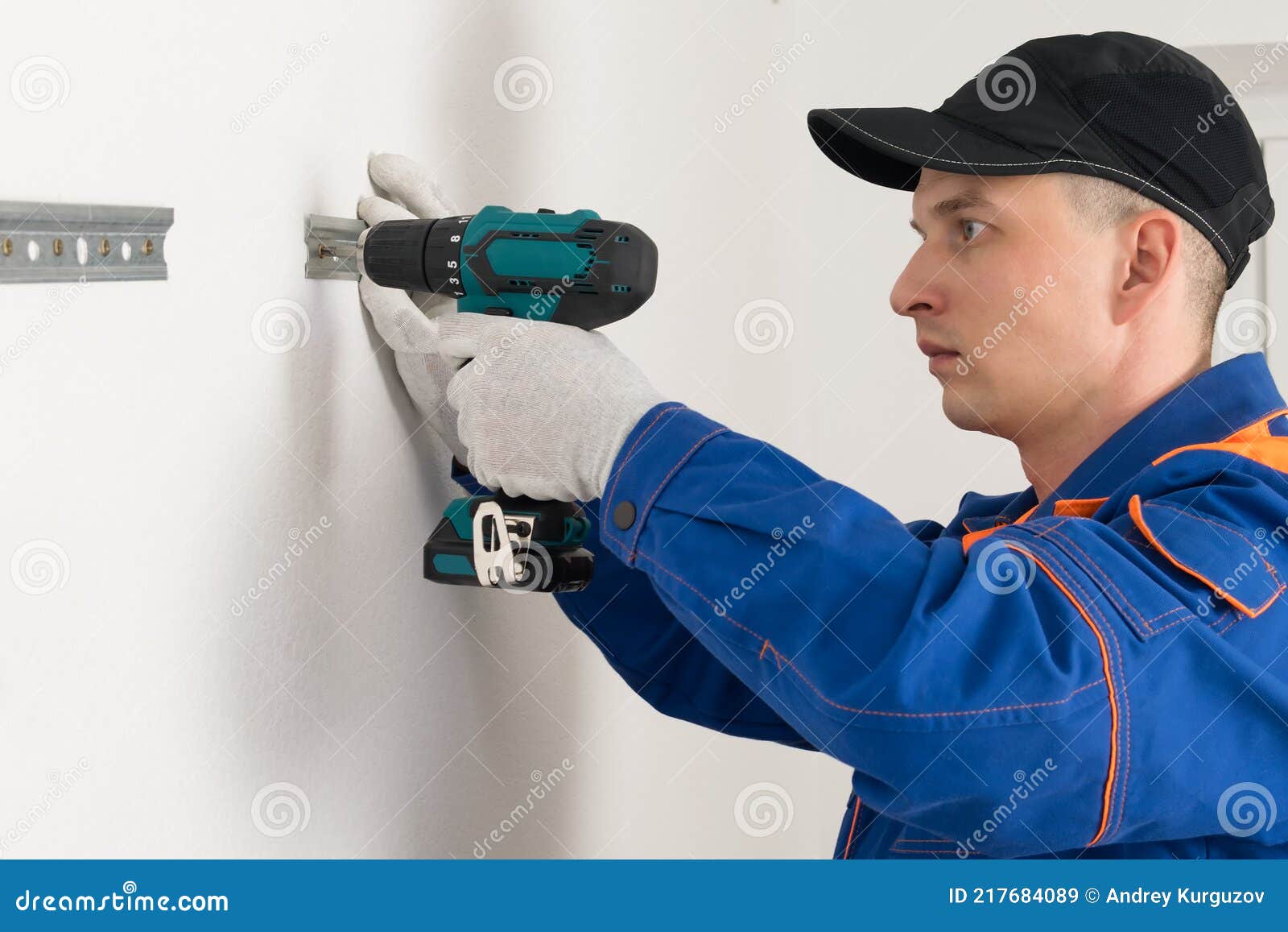 A Worker Screws Fasteners To a White Wall with Selftapping Screws for