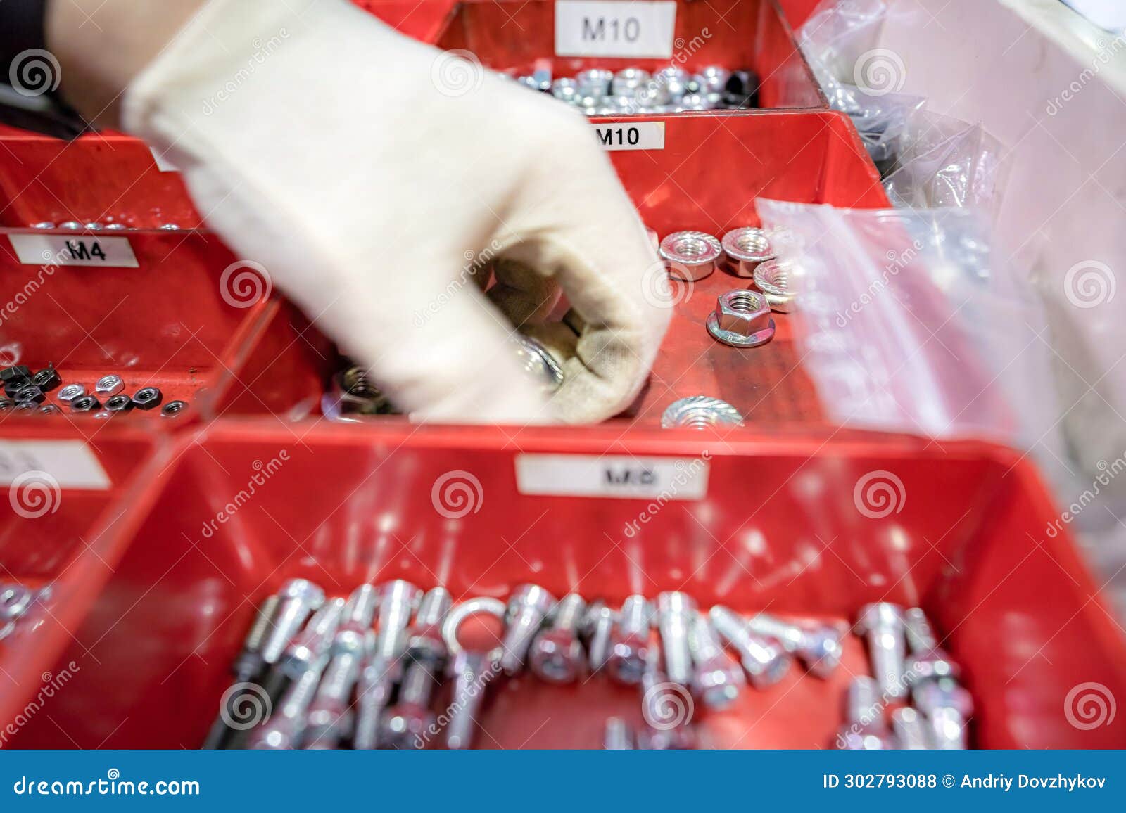 A Worker Selects Bolts and Nuts for Work from a Box of Hardware Stock