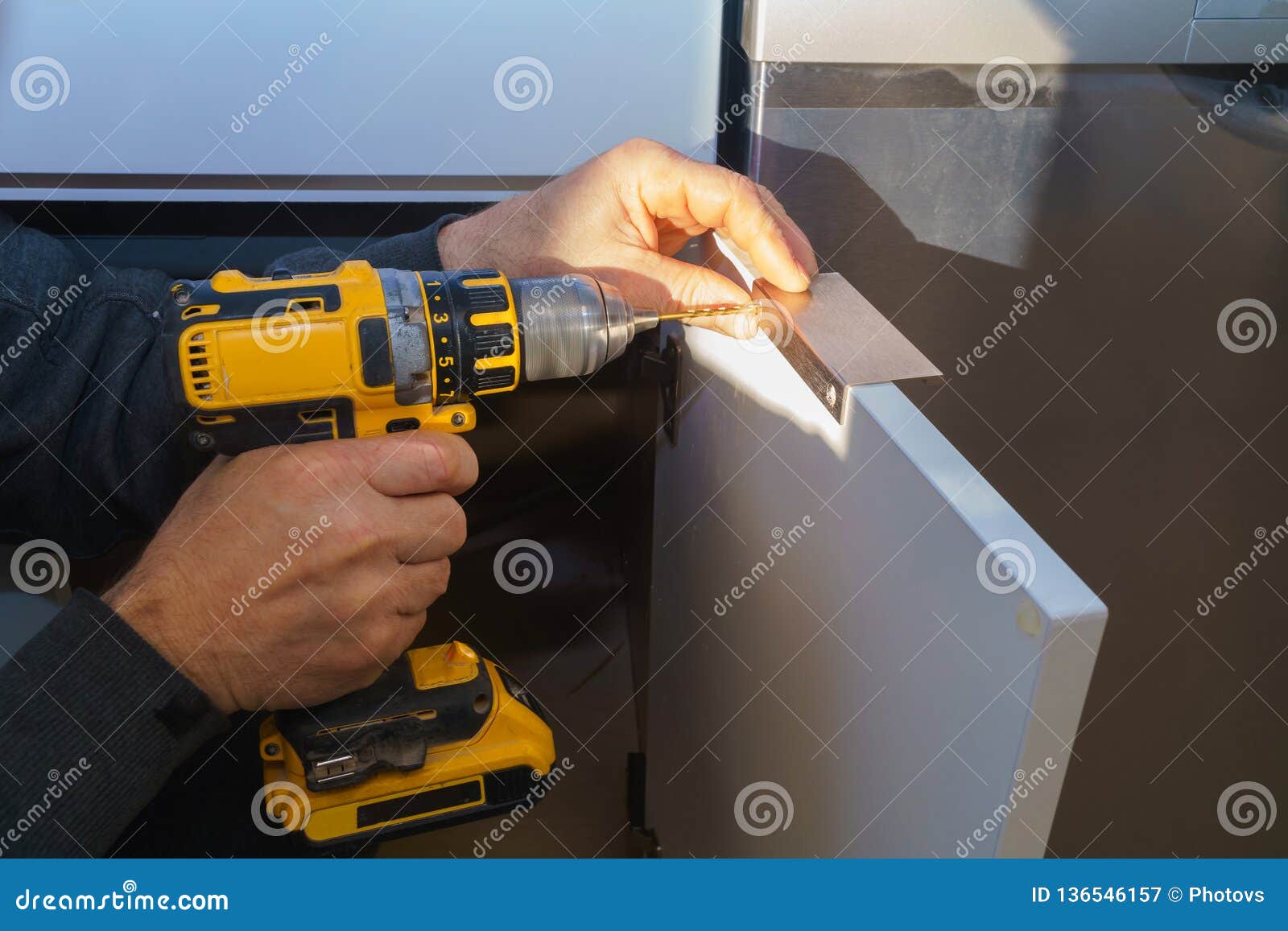 Worker Sets a New Handle on the White with a Screwdriver Installing Kitchen