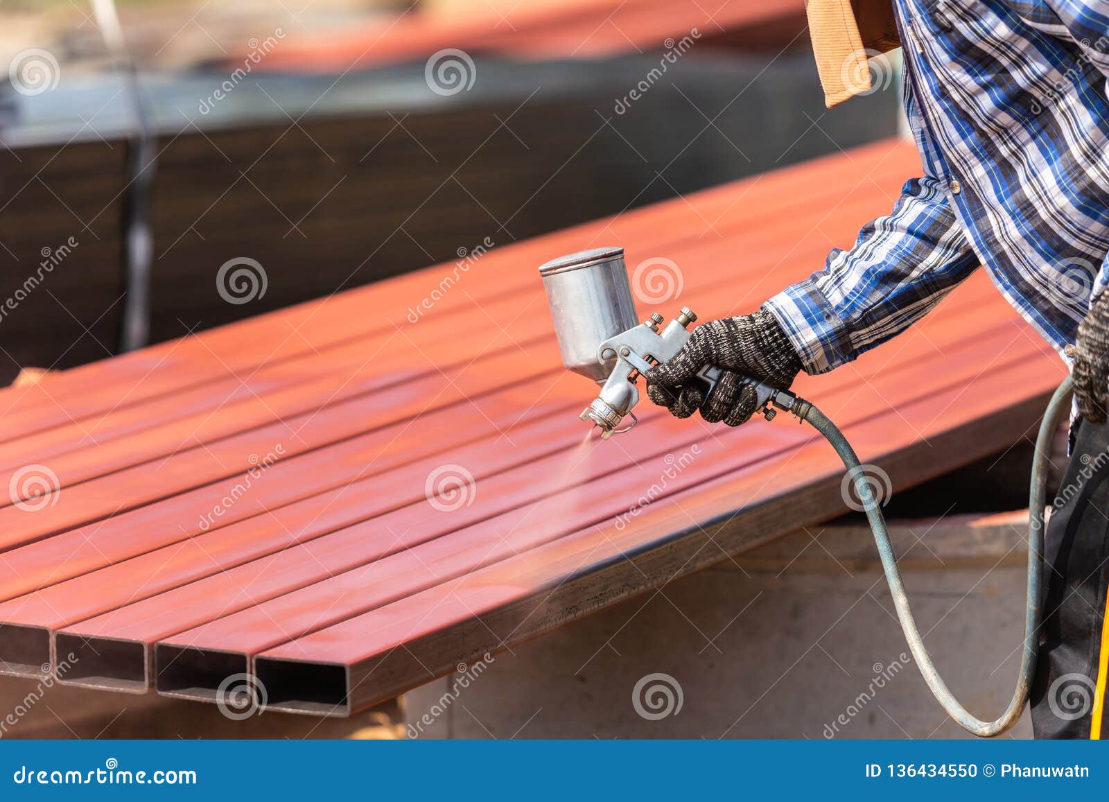 worker spraying paint to steel pipe to prevent the rust on the surface