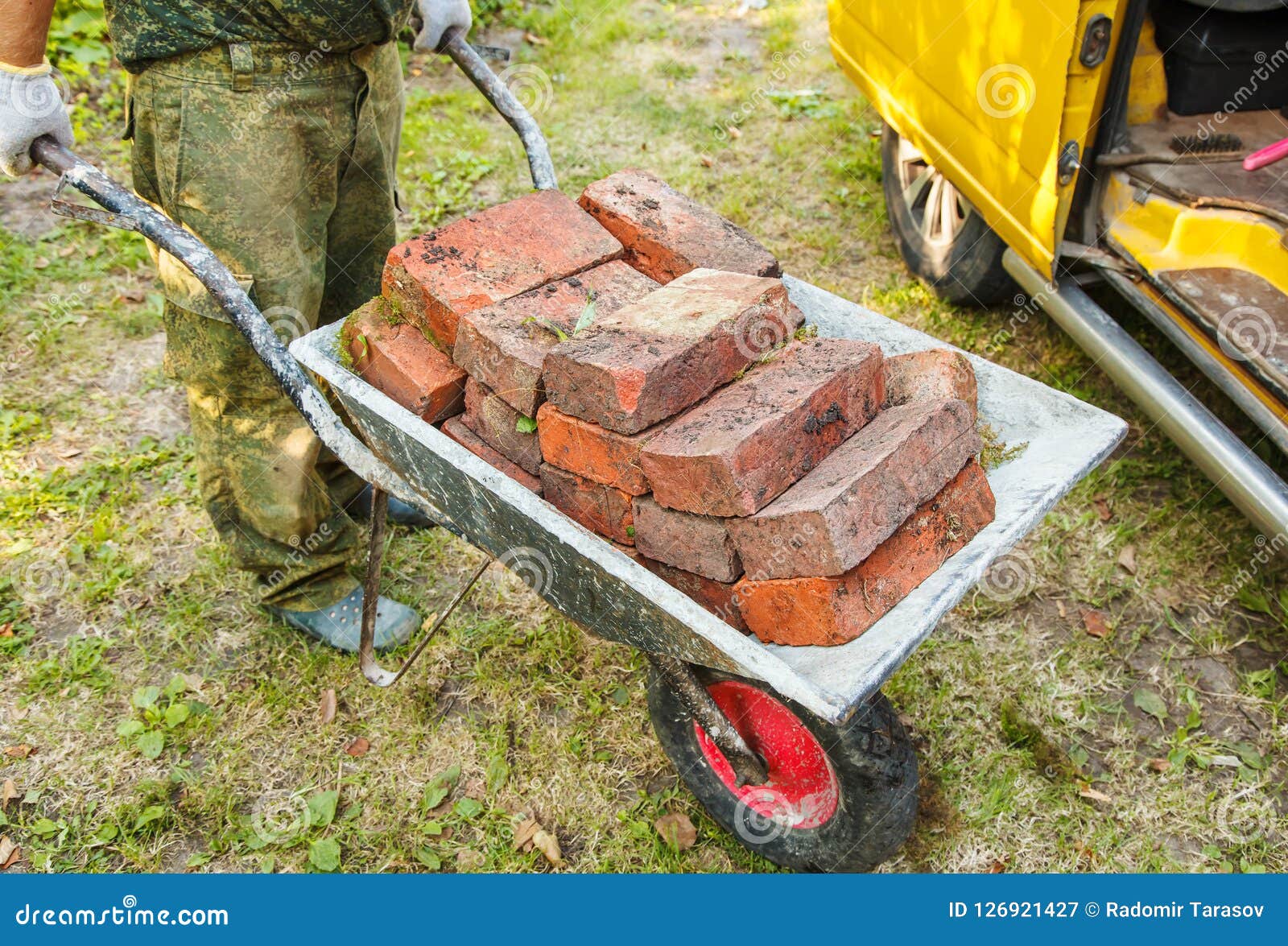 worker-transporting-brick-wheelbarrow-outdoor-summer-day-worker-transporting-brick-wheelbarrow-126921427.jpg