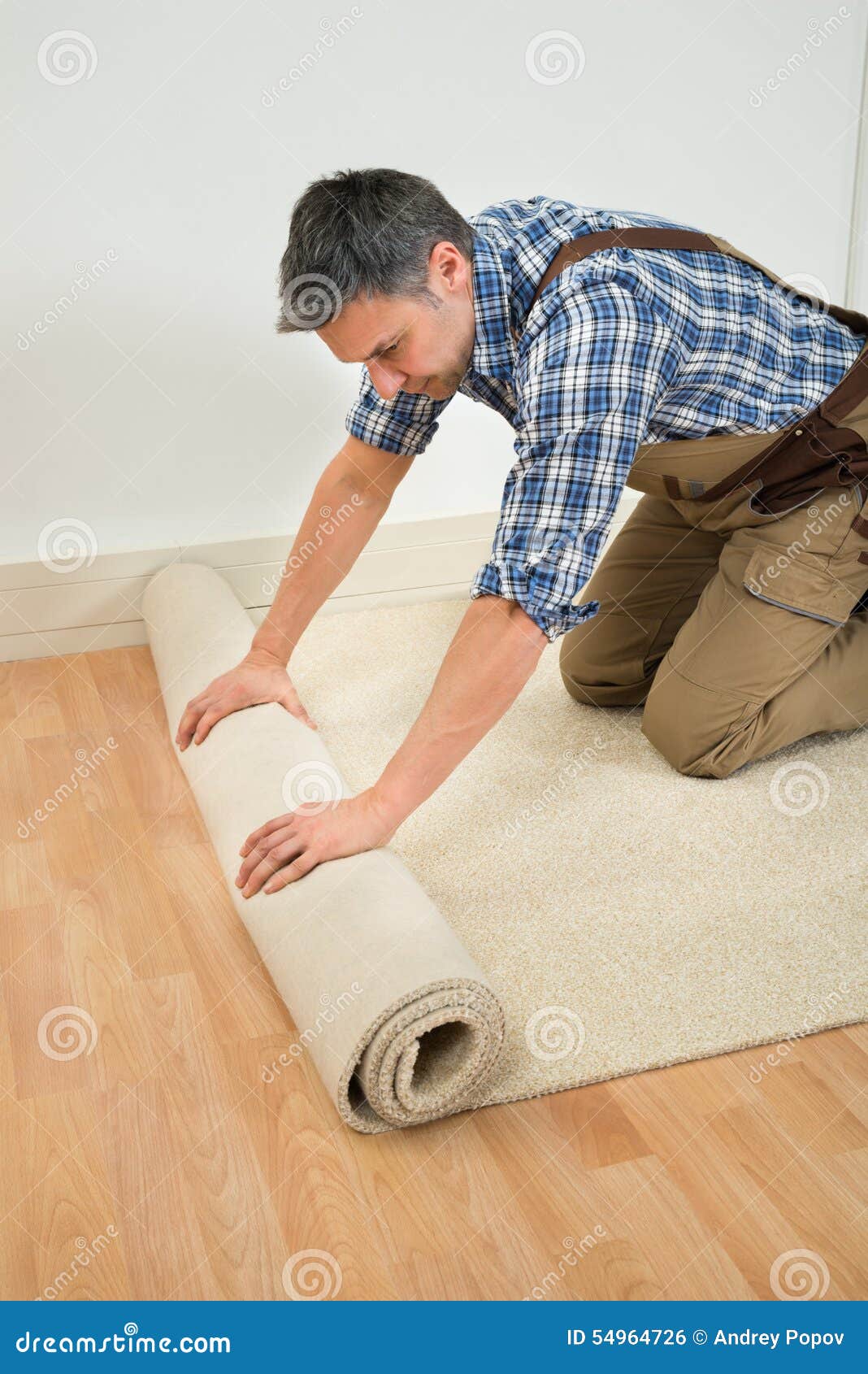 worker unrolling carpet on floor