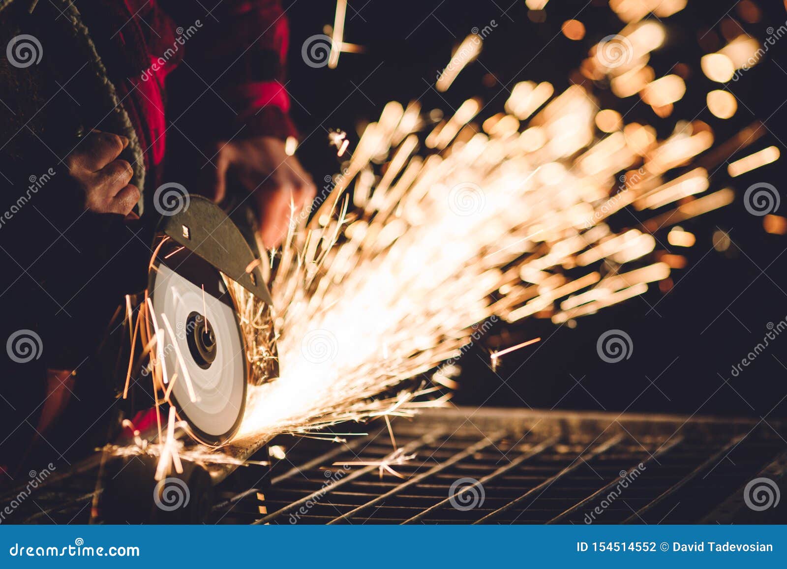 Worker Using Angle Grinder in Factory and Throwing Sparks. Stock Photo