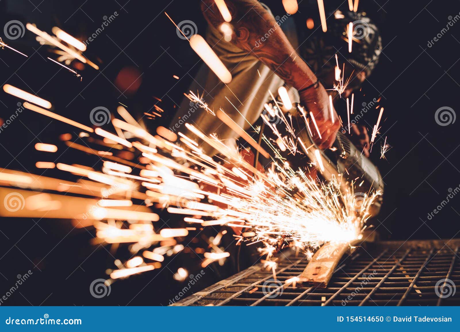 Worker Using Angle Grinder in Factory and Throwing Sparks. Stock Photo
