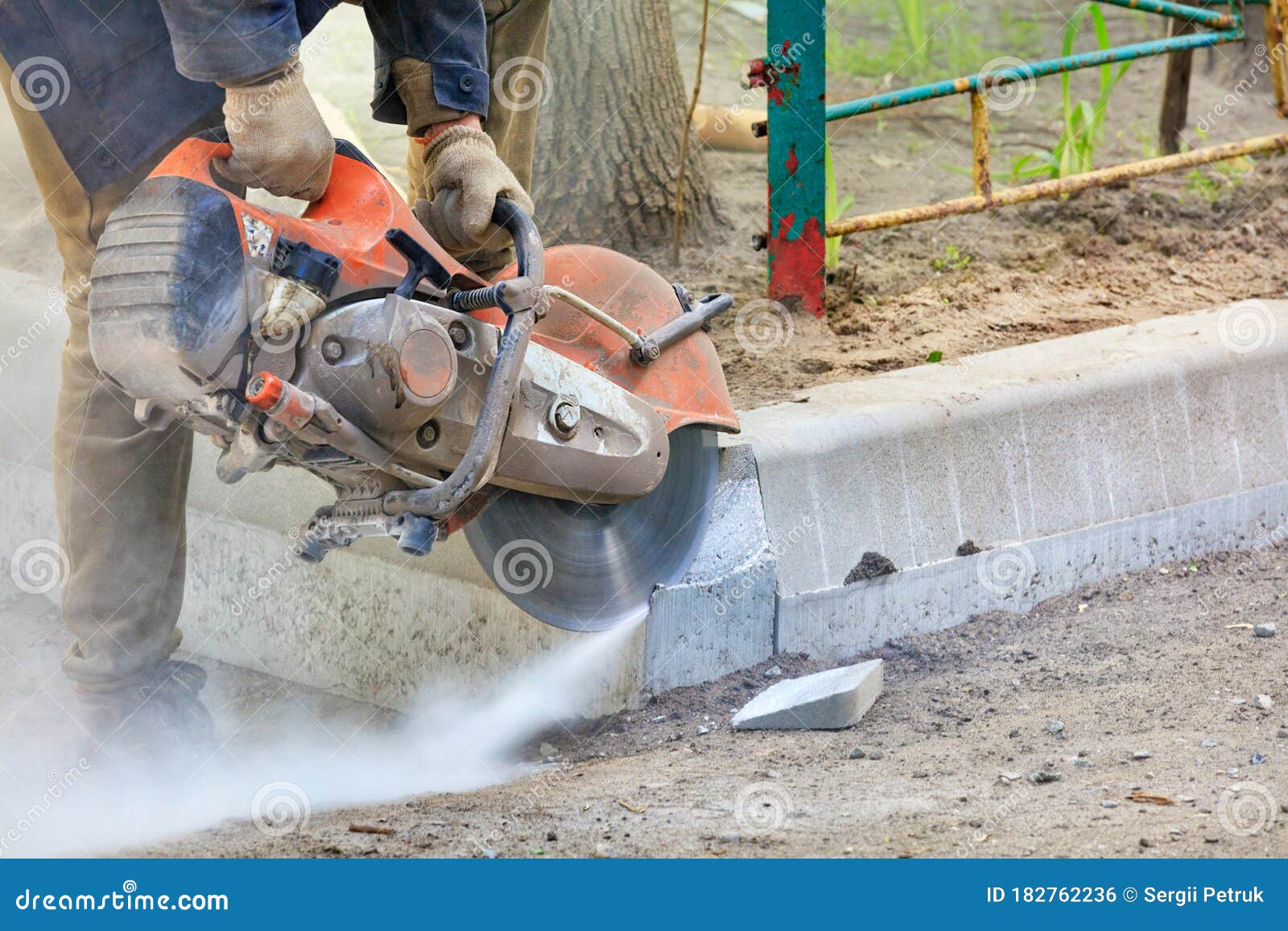 Worker at a Construction Site Using a Concrete Saw Cuts Concrete Curbs