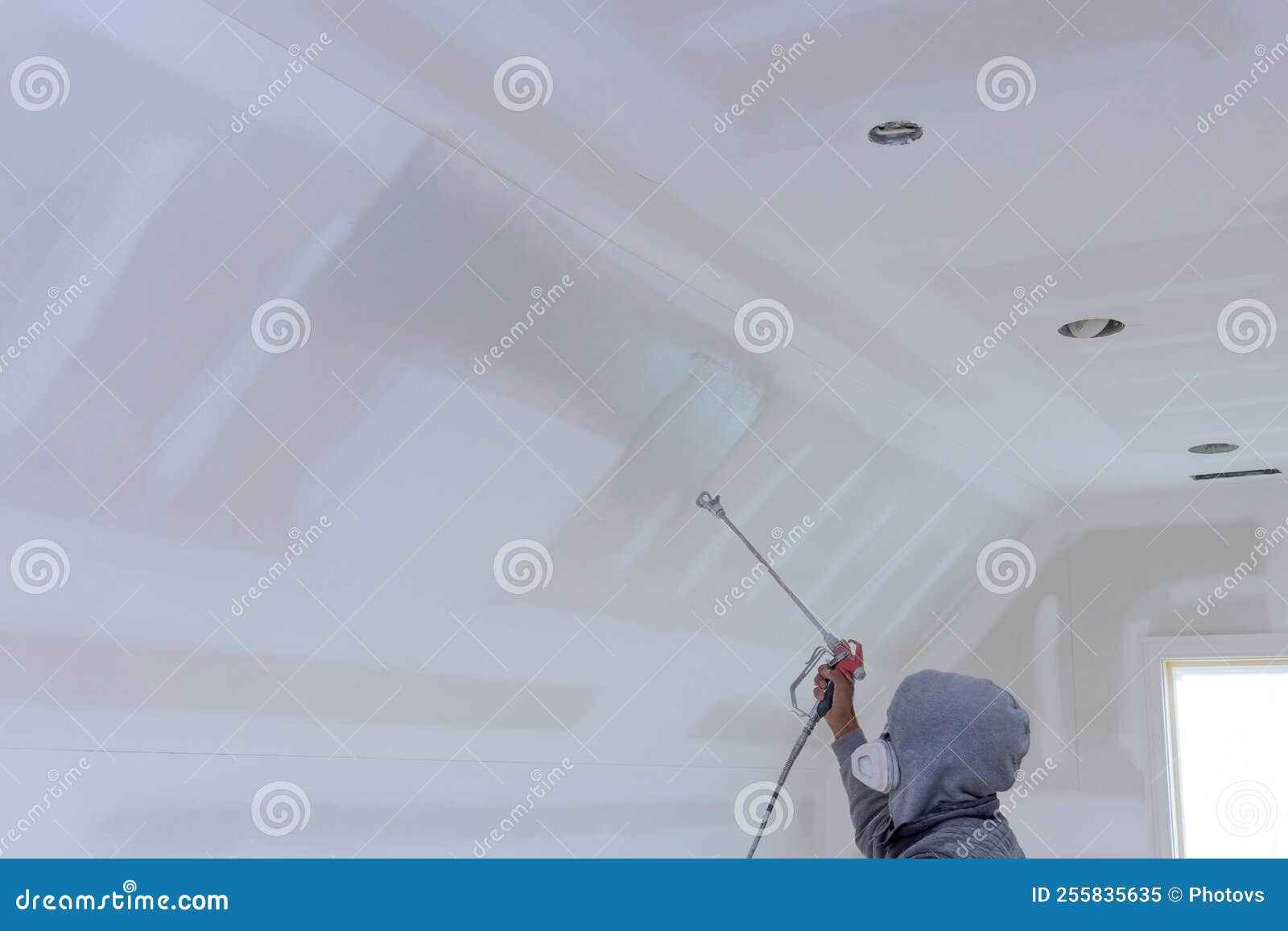 The Worker Using Spray Gun with a Primer Paint Walls and Ceiling Stock