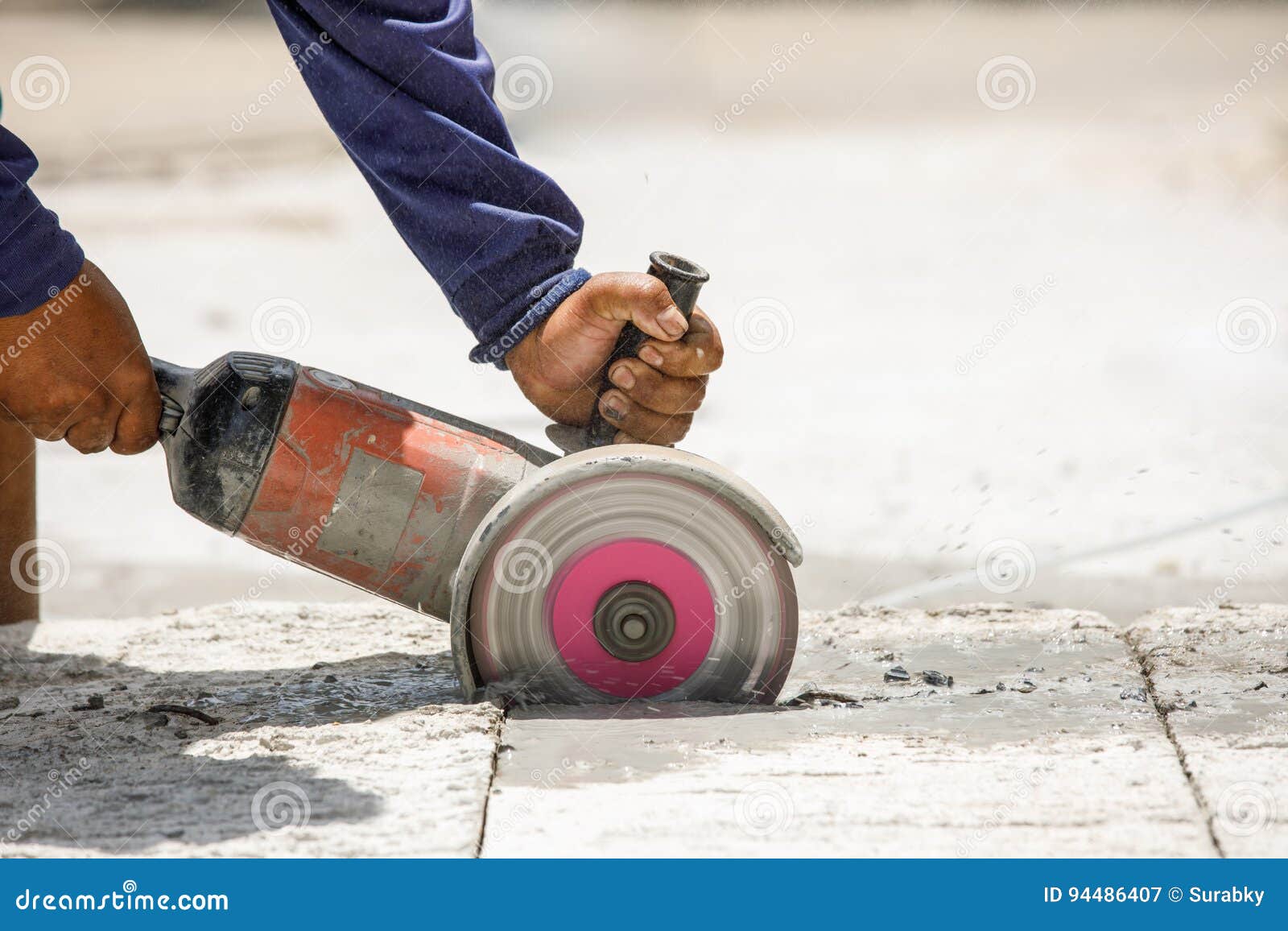 Worker Using Tool To Cut Concrete Floor with Blank Space on Right Stock