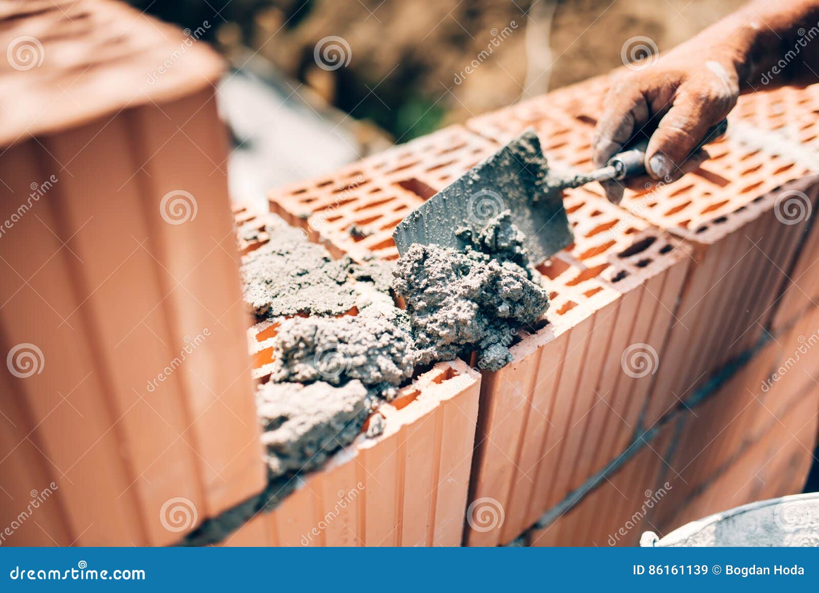 worker using trowel and tools for building exterior walls with bricks and mortar