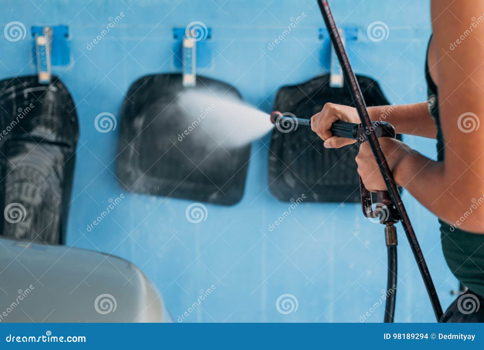 The Worker Washes Water Under Pressure Carpets from the Car at the Car