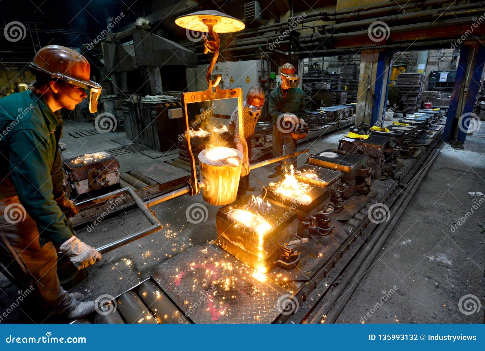 workers in a foundry casting a metal workpiece - safety at work and teamwork
