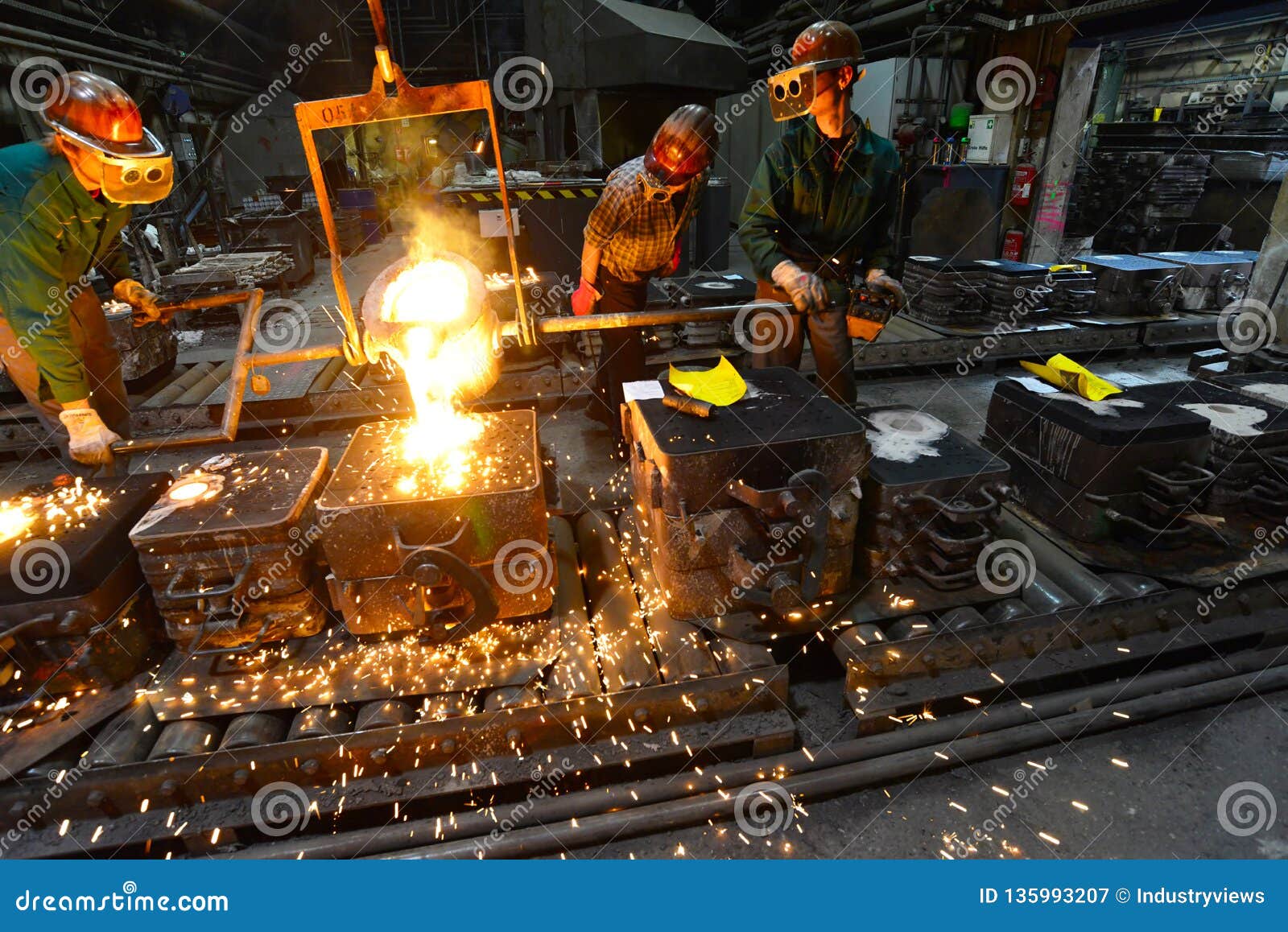 workers in a foundry casting a metal workpiece - safety at work and teamwork