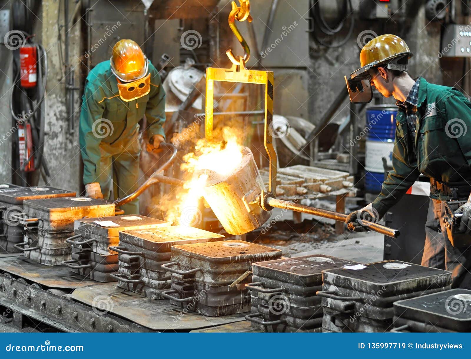 workers in a foundry casting a metal workpiece - safety at work and teamwork