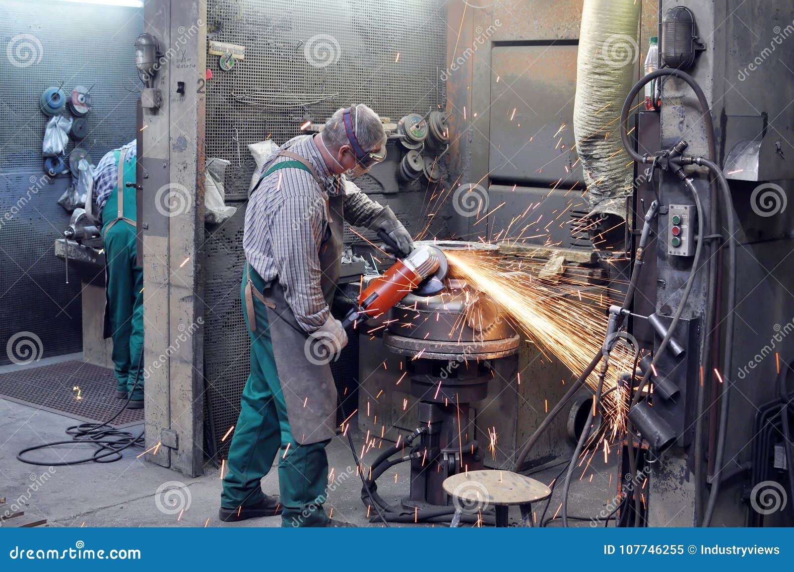 workers in a foundry grind castings with a grinding machine - he