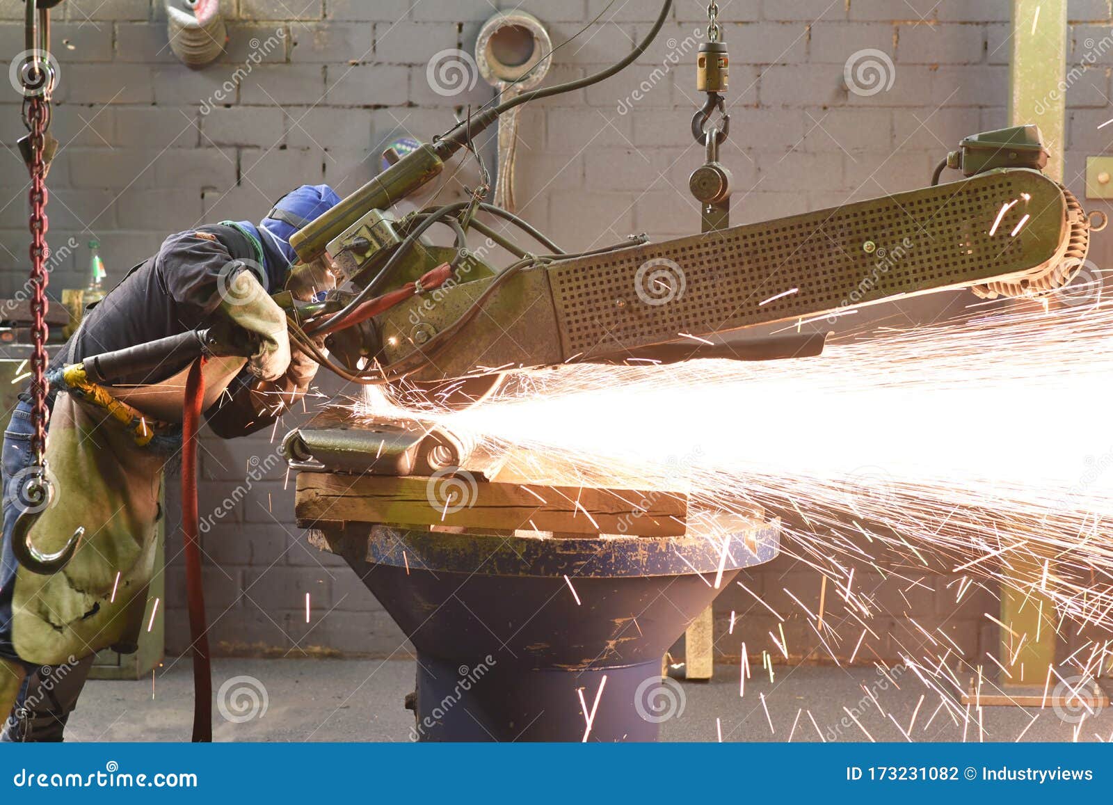 workers in protective equipment in a foundry work on a casting with a grinding machine at the workplace