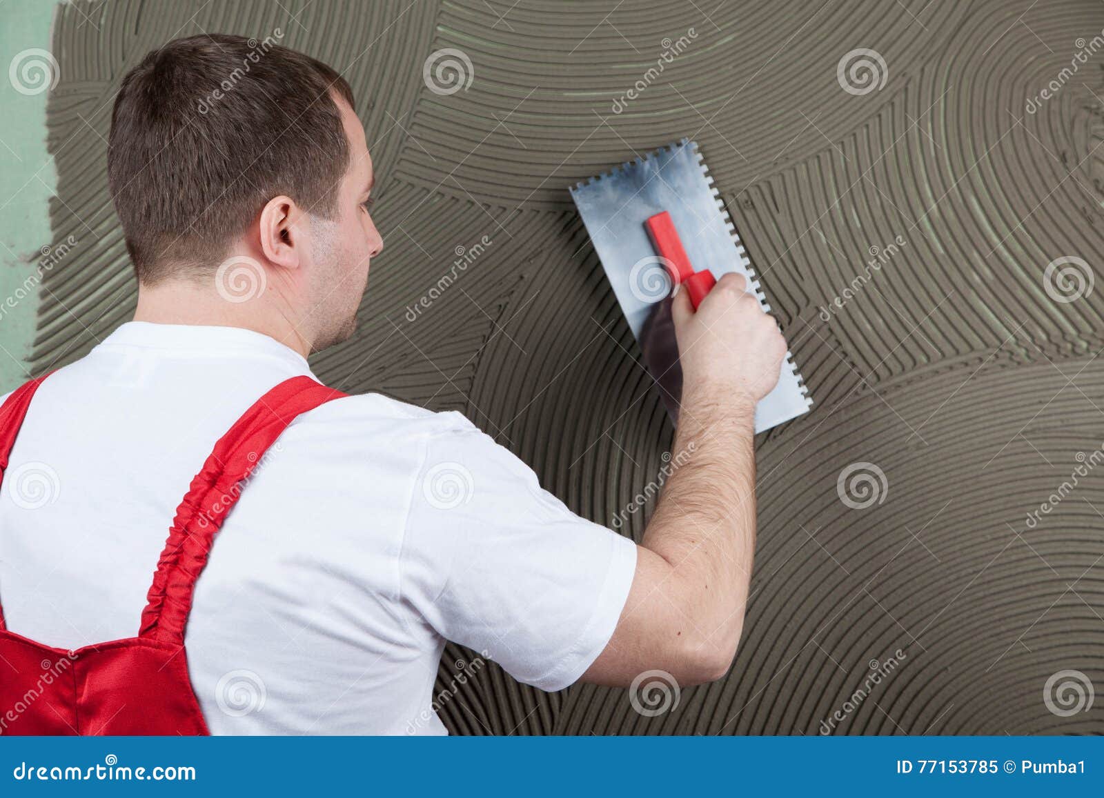 The Working Builder Applies Glue on a Wall for a Ceramic Tile. F Stock