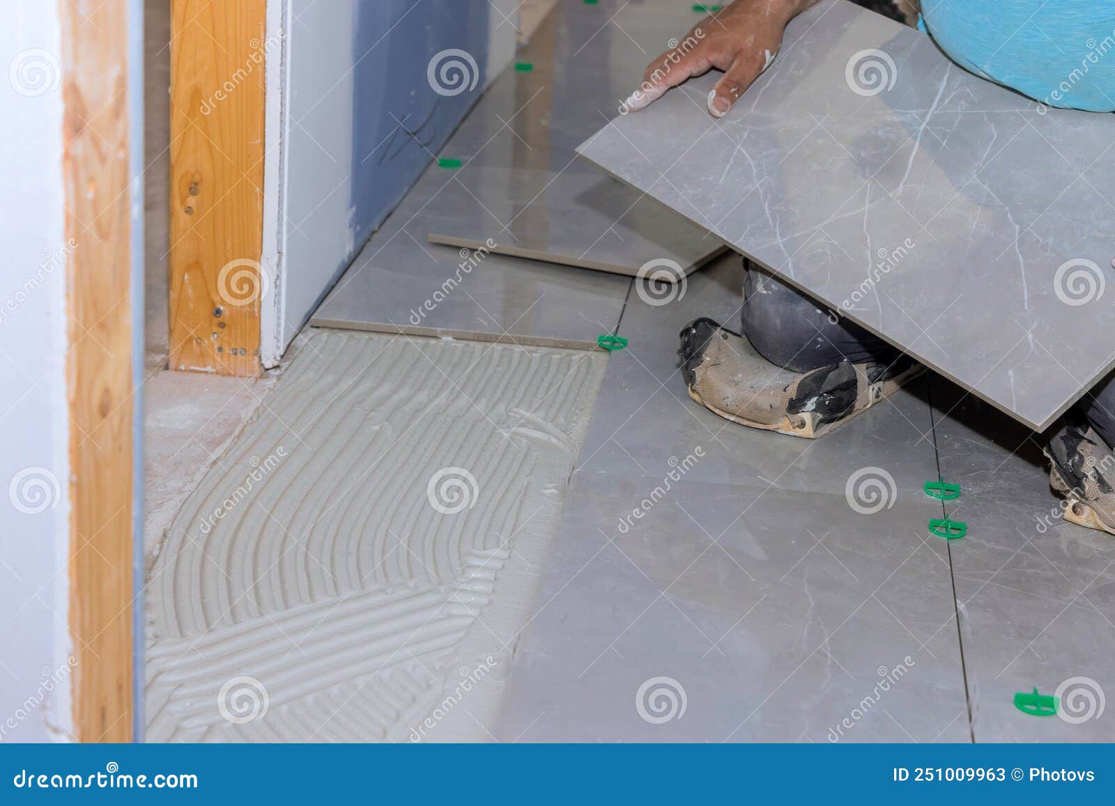 Working on a Home Construction Project Laying Ceramic Floor Tiles on an