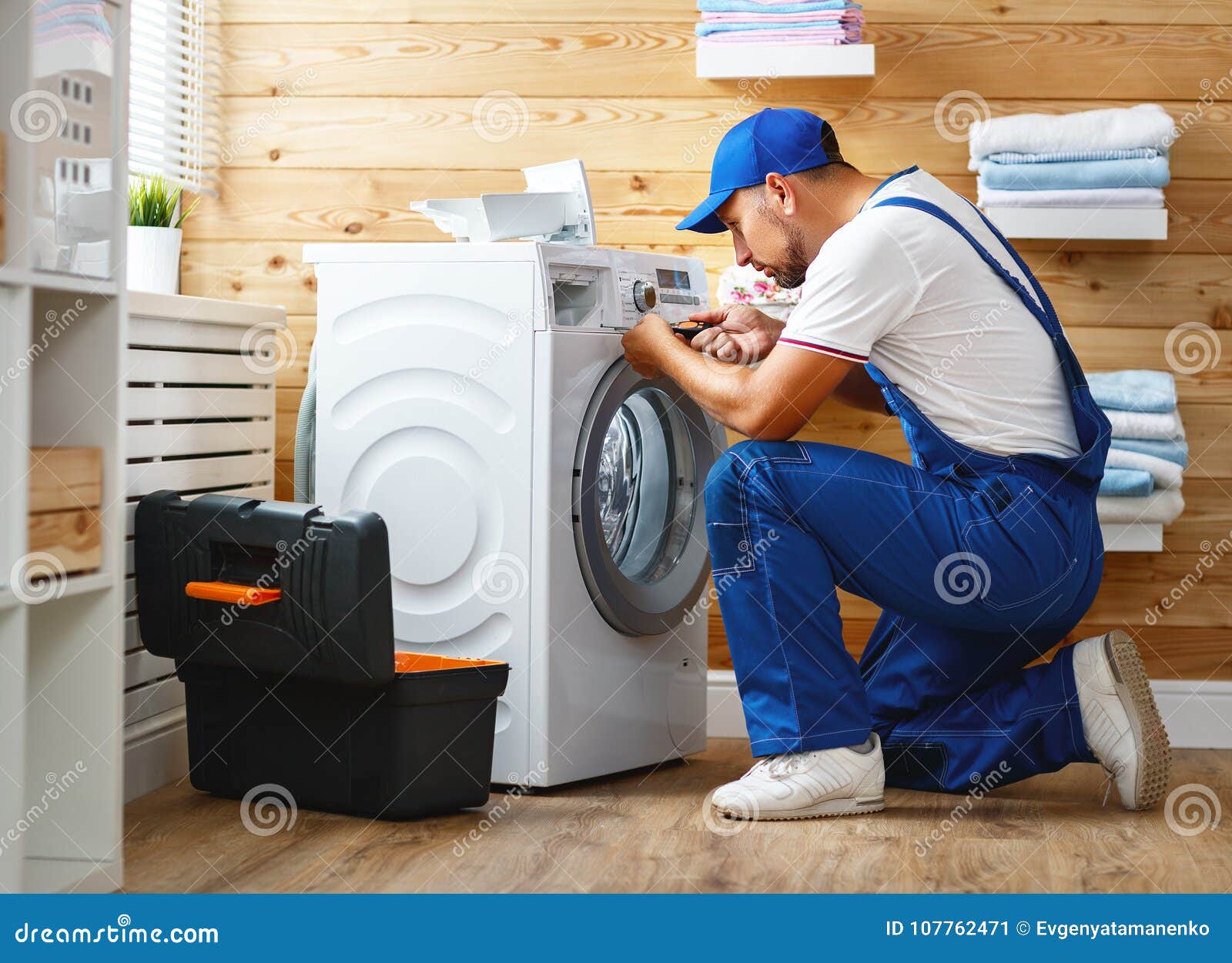 working man plumber repairs washing machine in laundry