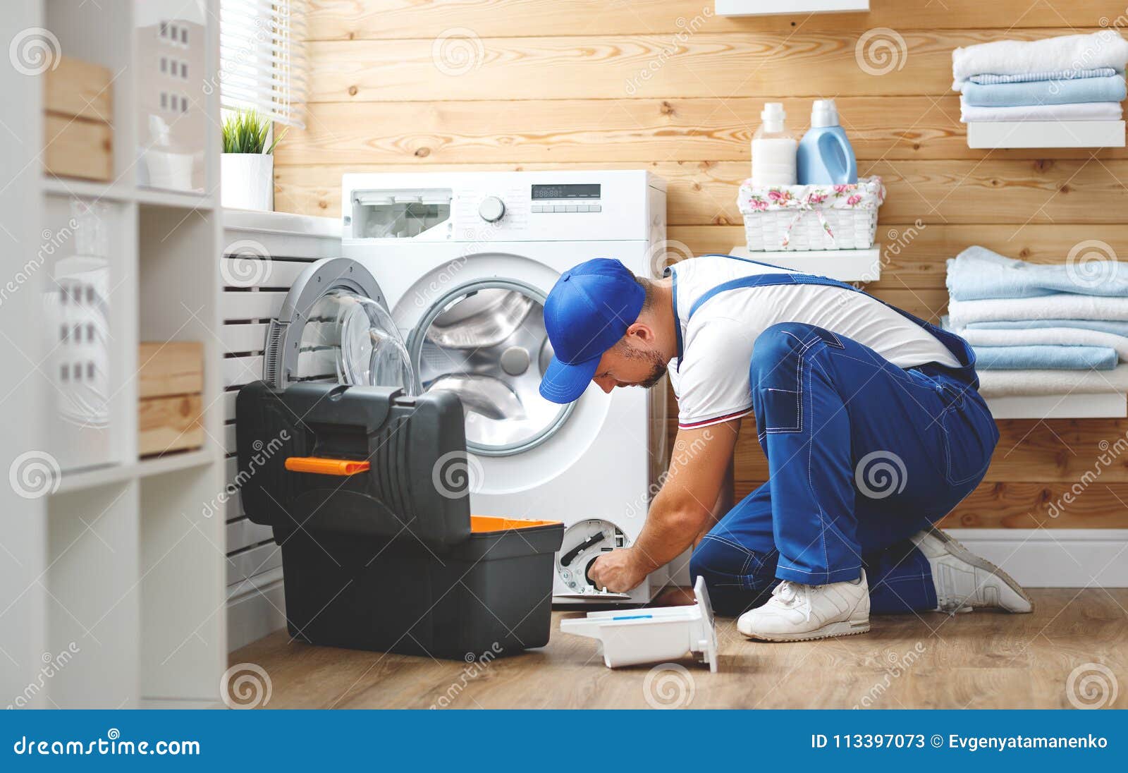 working man plumber repairs washing machine in laundry