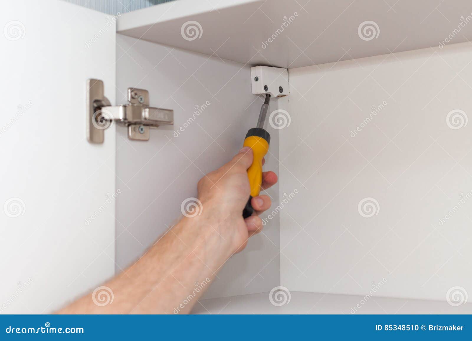 A Workman Fixing with Screwdriver in Kitchen. Stock Photo Image of furniture, person