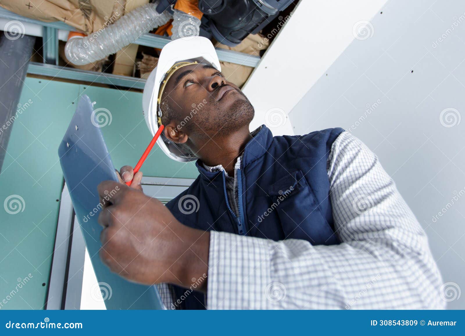 workman looking at ventilation system and making notes on clipboard