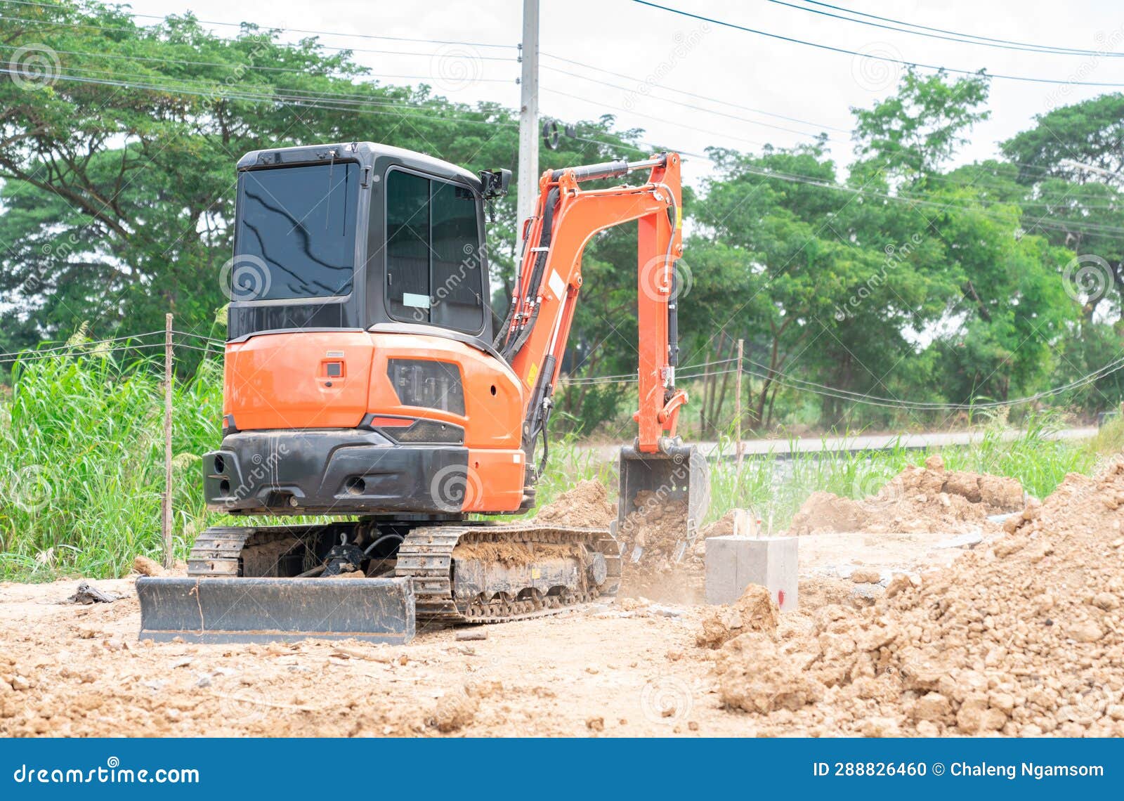 Workman Using a Mini Digger To Cover Up a Hole of Foundation Pile Stock