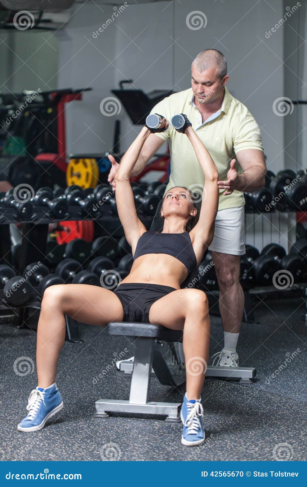 Workout With Personal Trainer. Woman at the health club with her personal trainer, learning the correct form with barbell