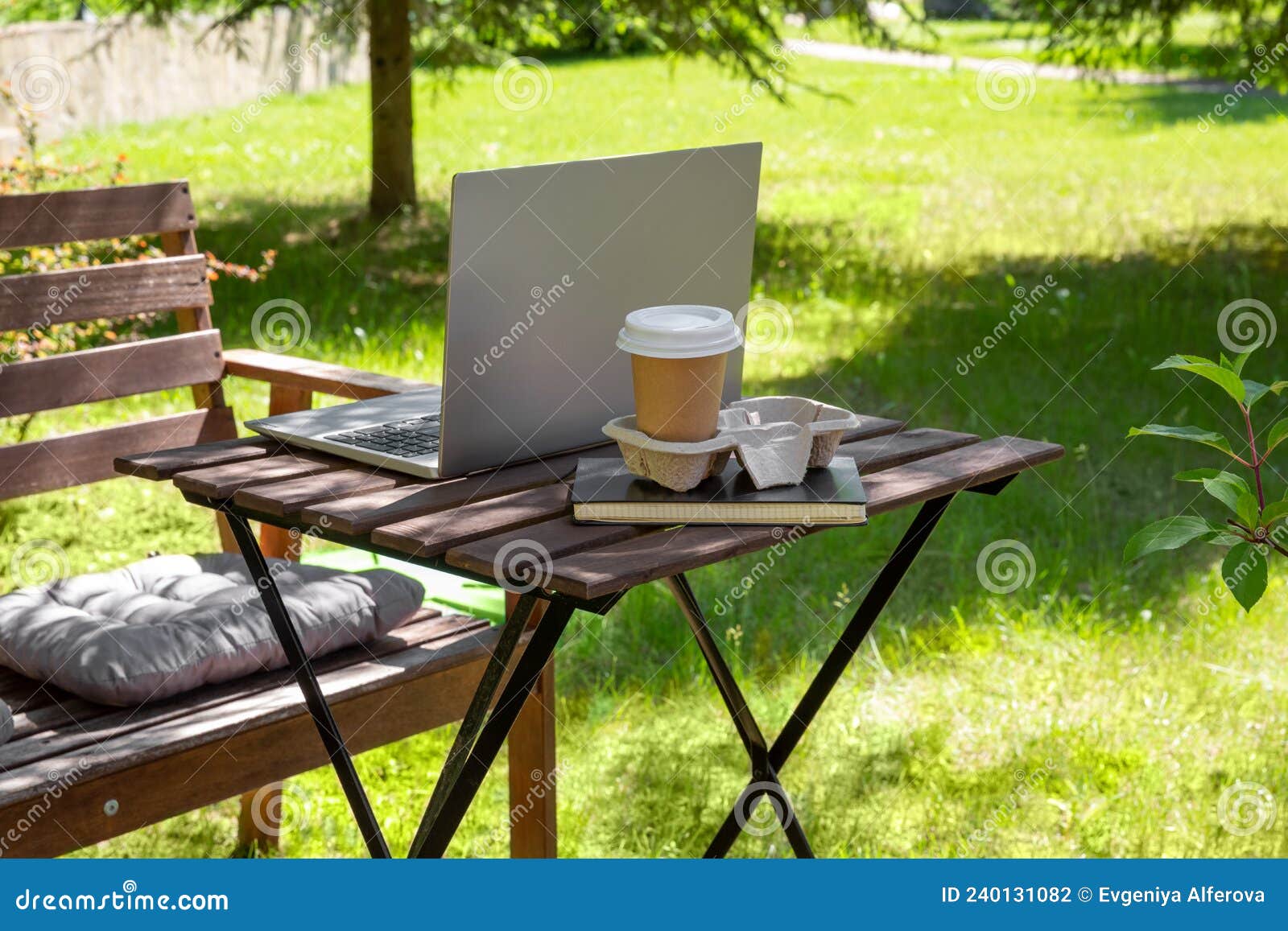Workplace with Laptop and Cup of Coffee in Garden. Working from Home