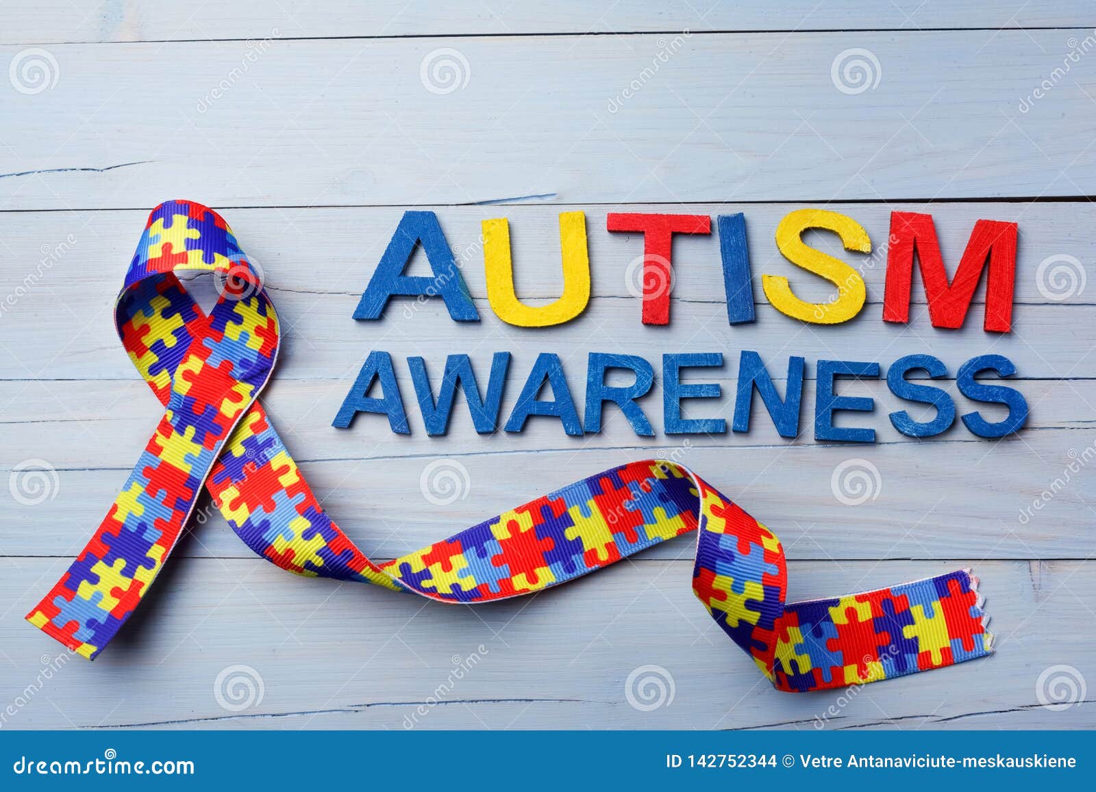 world autism awareness and pride day or month with puzzle pattern ribbon on blue wooden background.