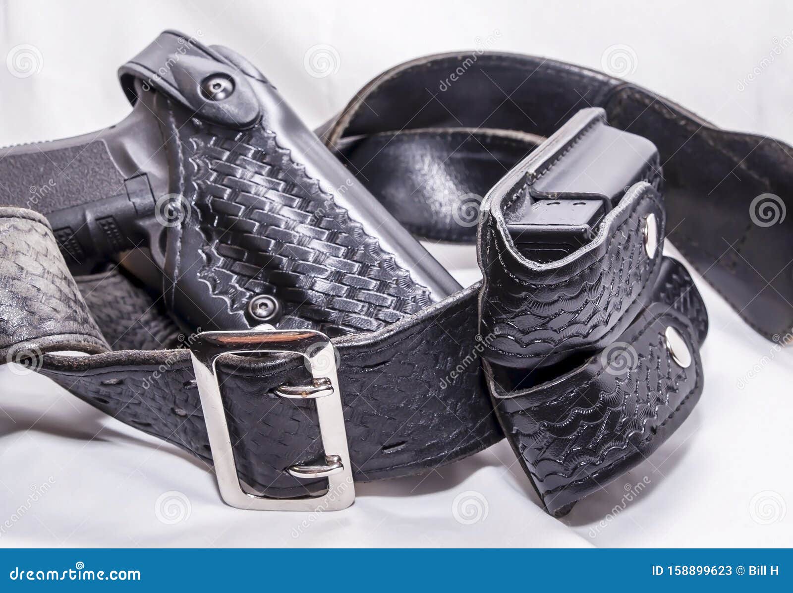 a worn police duty belt with a black pistol and two pistol magazine case wrapped up