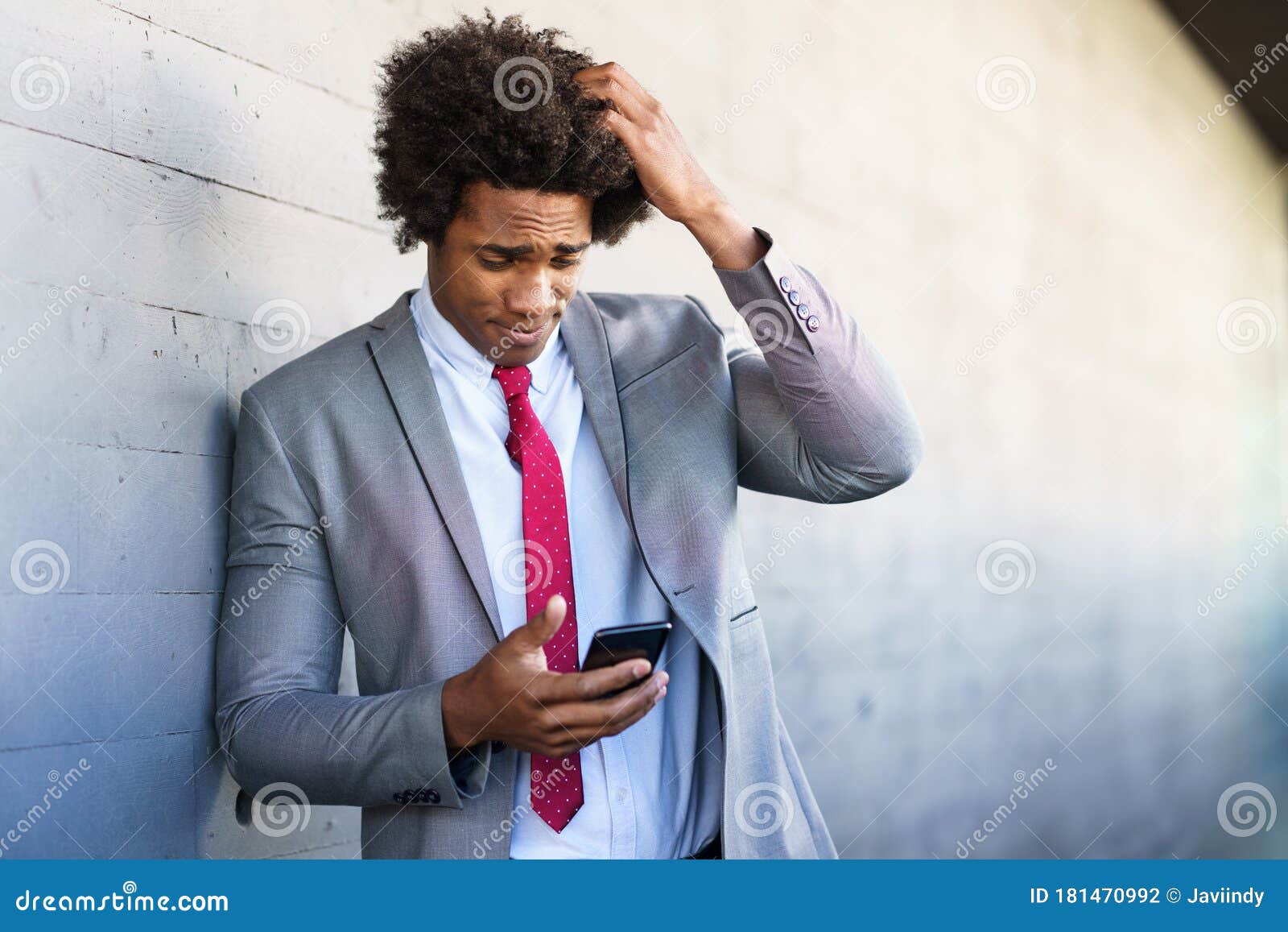 worried black businessman using his smartphone outdoors.